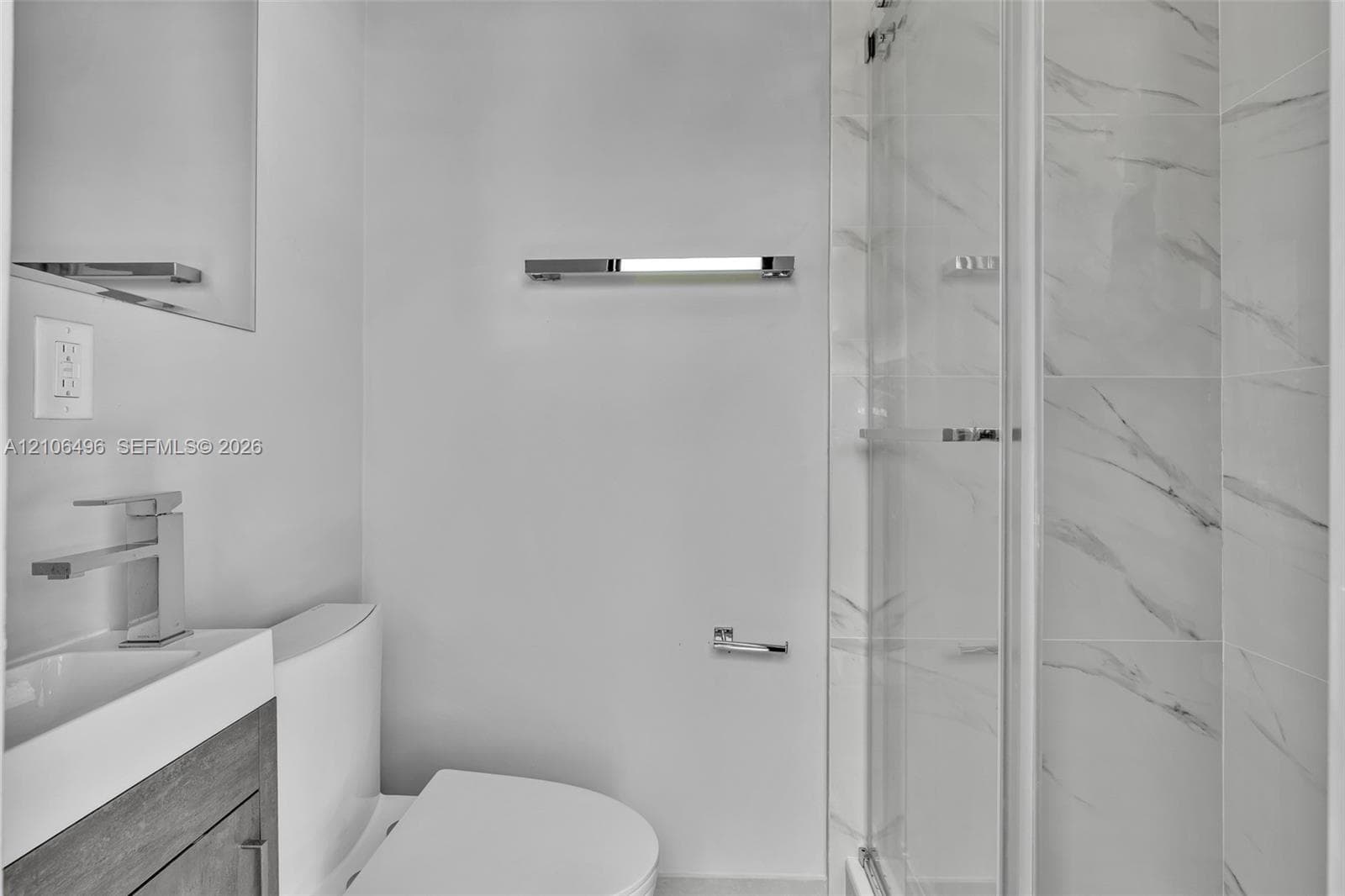 Modern bathroom featuring a wood-finish vanity, rectangular vessel sink with a polished chrome faucet, glass-enclosed shower with tiled walls, and polished chrome hardware