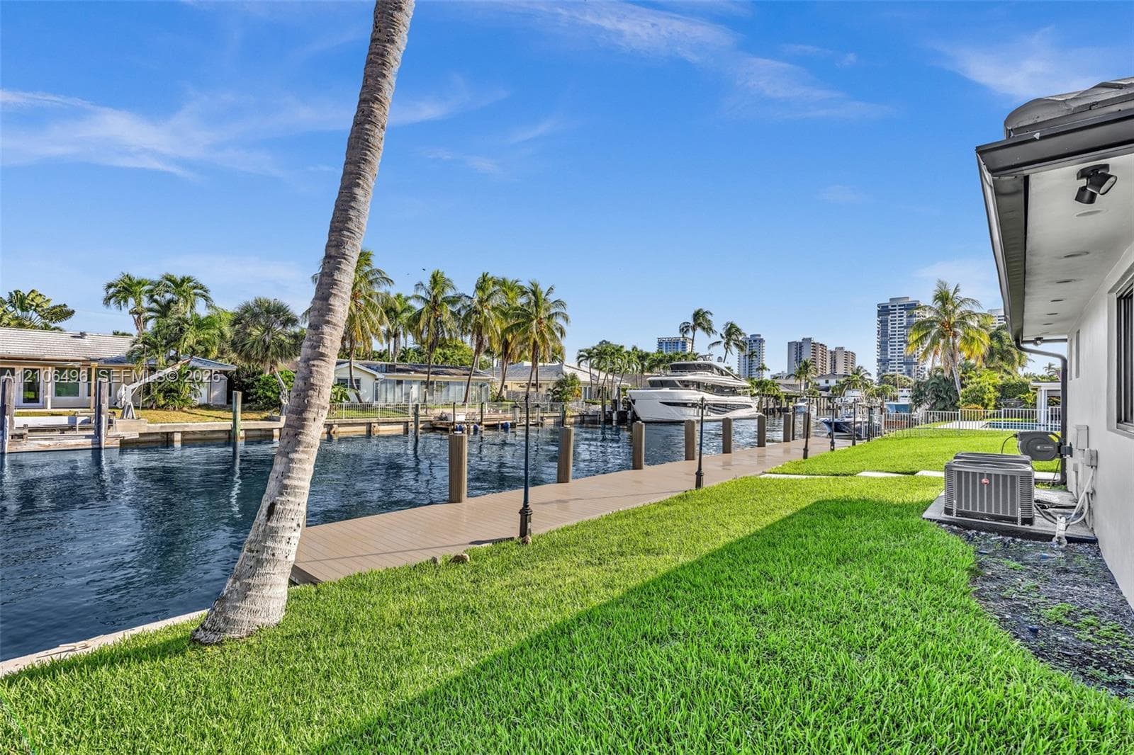 Waterfront property featuring a private dock, bulkhead, and manicured lawn