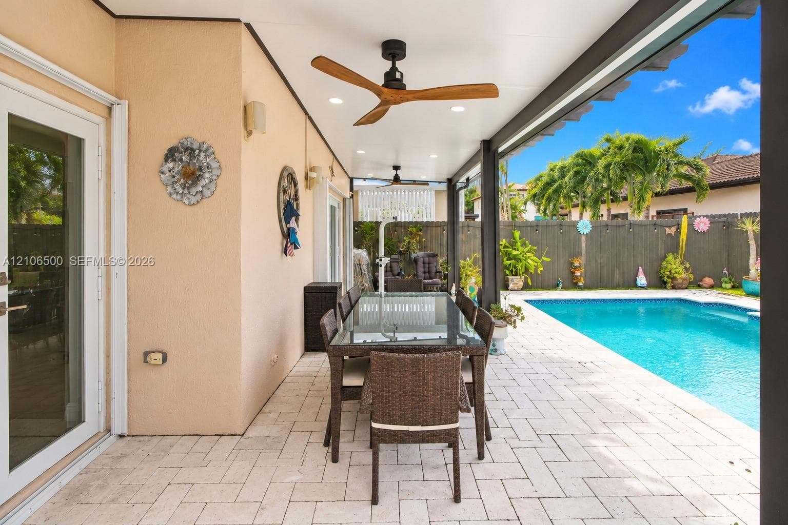 Covered patio featuring recessed lighting, ceiling fans with wood-finish blades, paver flooring, and a swimming pool