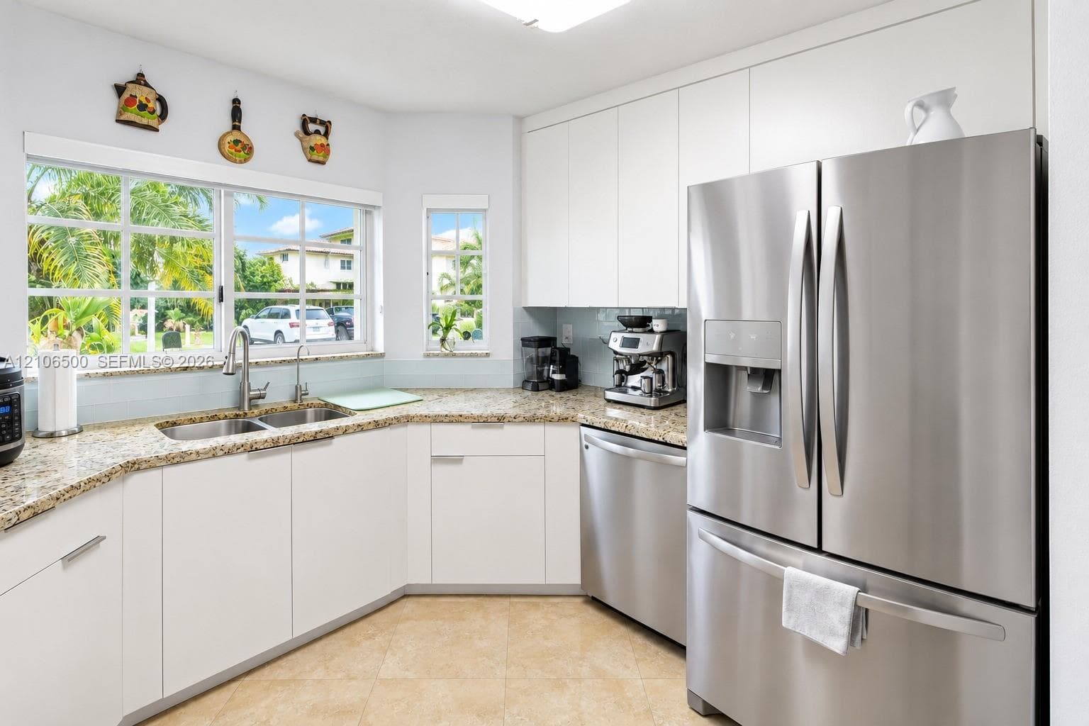 Kitchen featuring white flat-panel cabinetry, stone countertops, stainless steel appliances, dual-basin undermount sink, and tile flooring