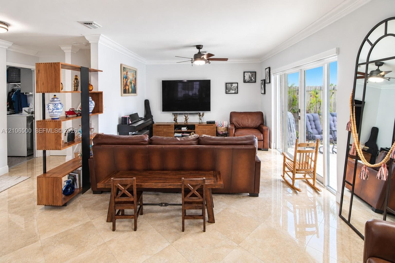 Living area featuring polished stone tile flooring, crown molding, a central ceiling fan, and sliding glass doors