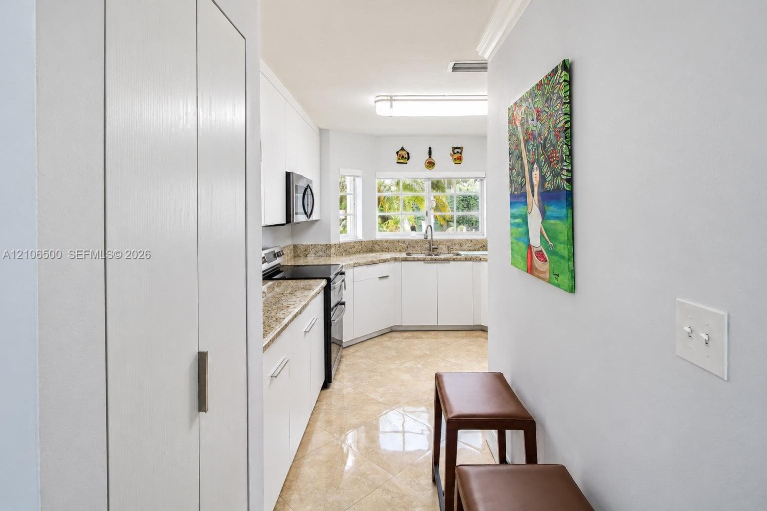 Kitchen featuring white cabinetry, stone-finish countertops, stainless steel appliances, tiled flooring, and a multi-pane window