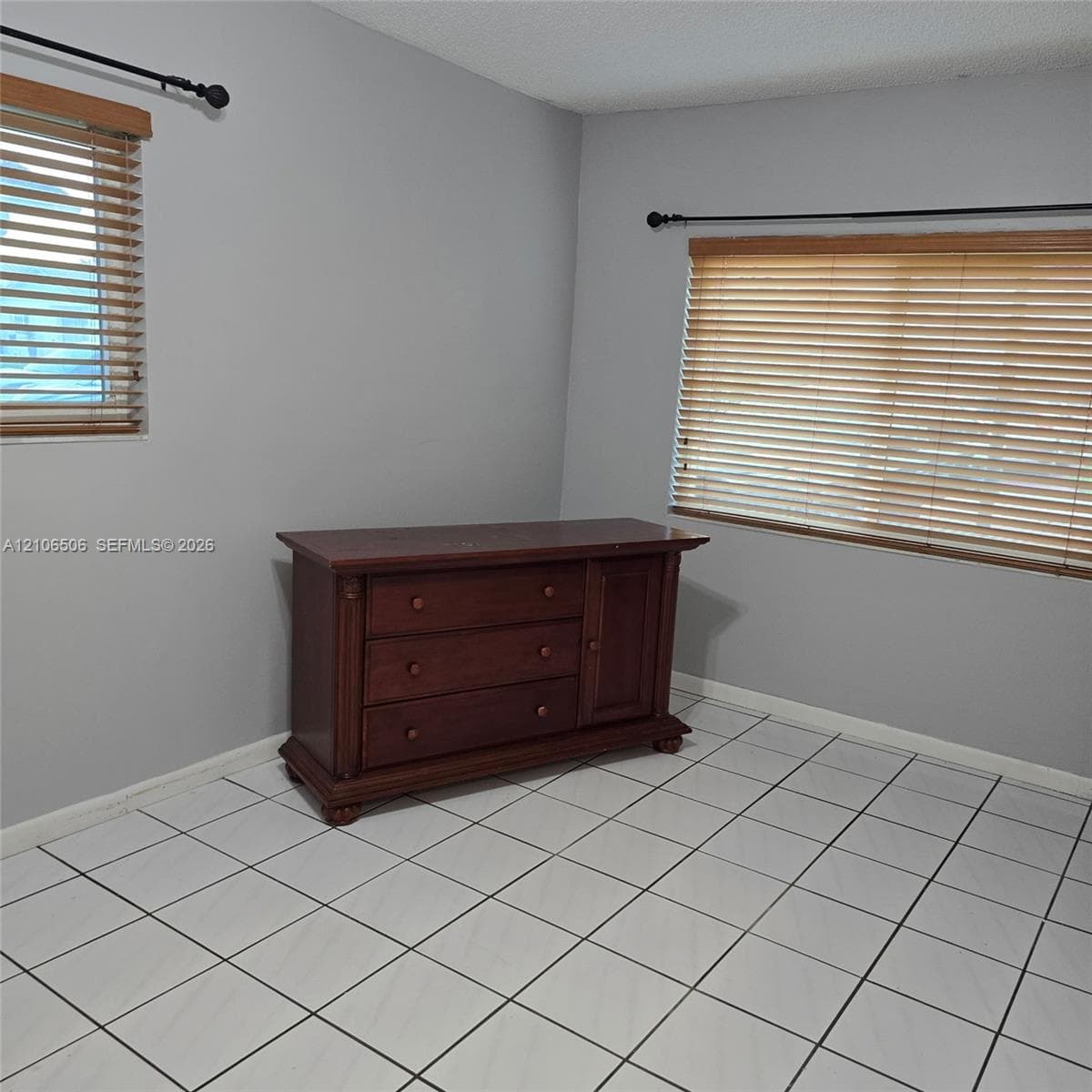 Neutral-toned walls featuring square tile flooring and windows equipped with horizontal blinds