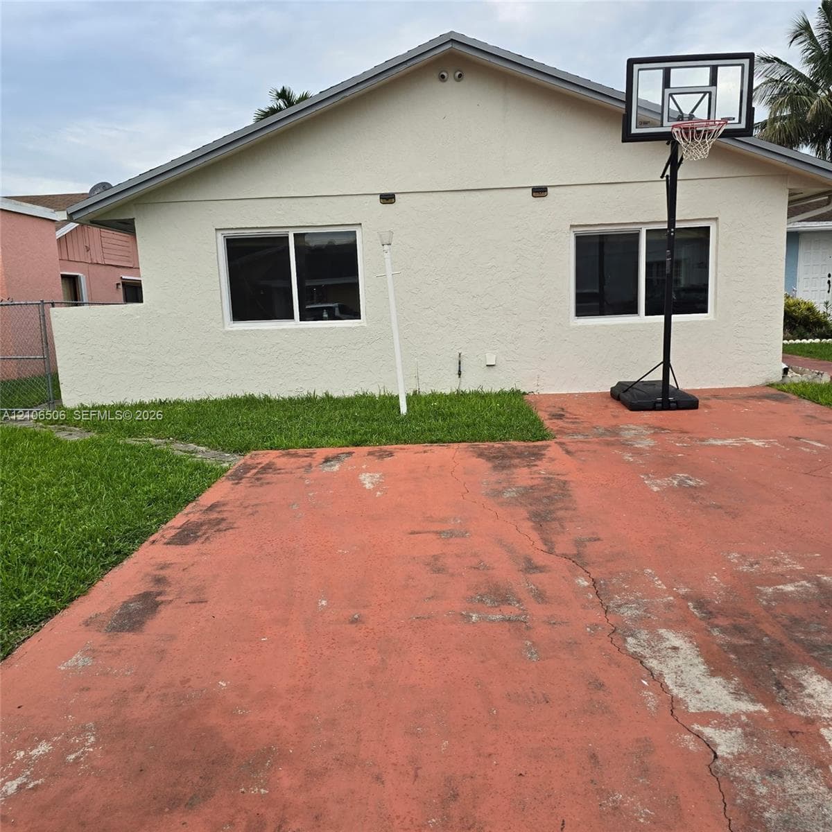 Stucco exterior, sliding windows, and paved concrete surface