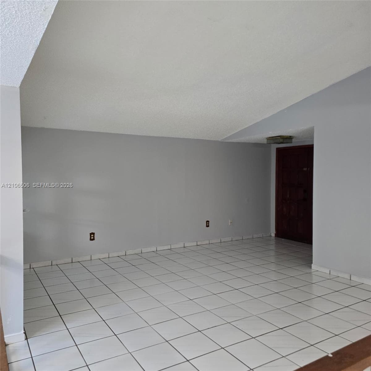 Interior space featuring vaulted ceilings, white tile flooring, and a solid wood entry door