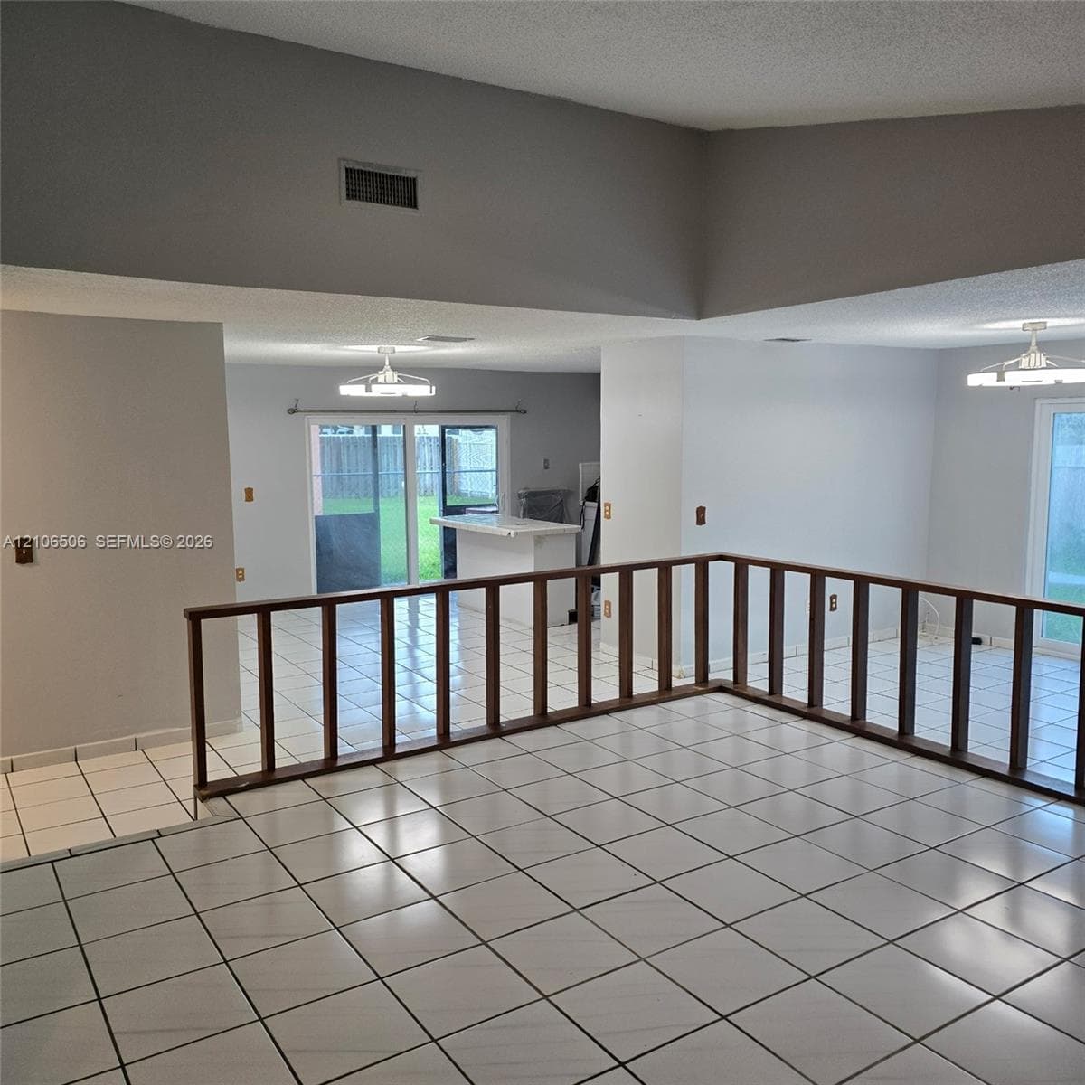 Vaulted ceiling, ceramic tile flooring, and custom wood-finished staircase railing