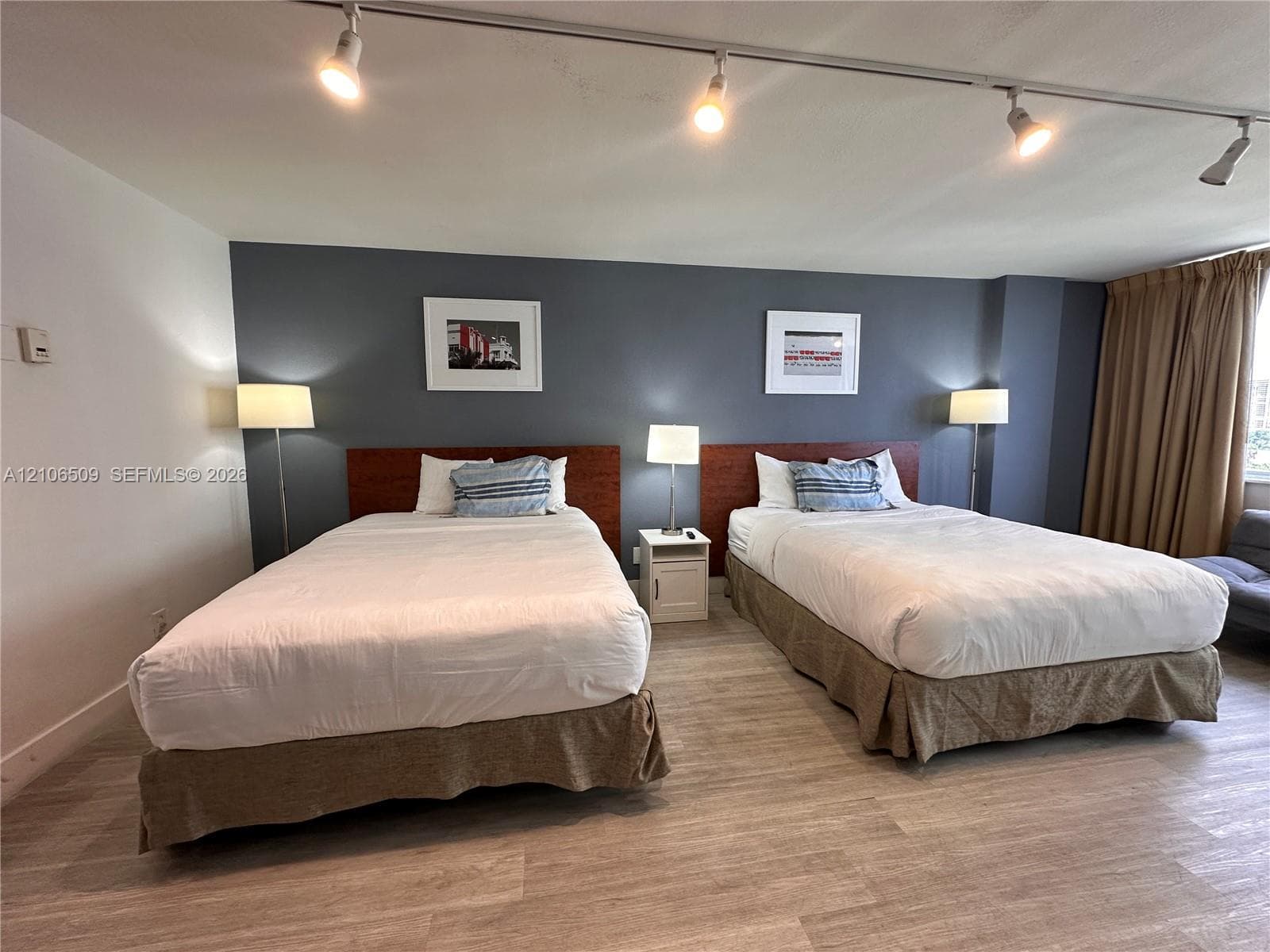 Wood-finish flooring, dark-toned accent wall, and ceiling-mounted track lighting