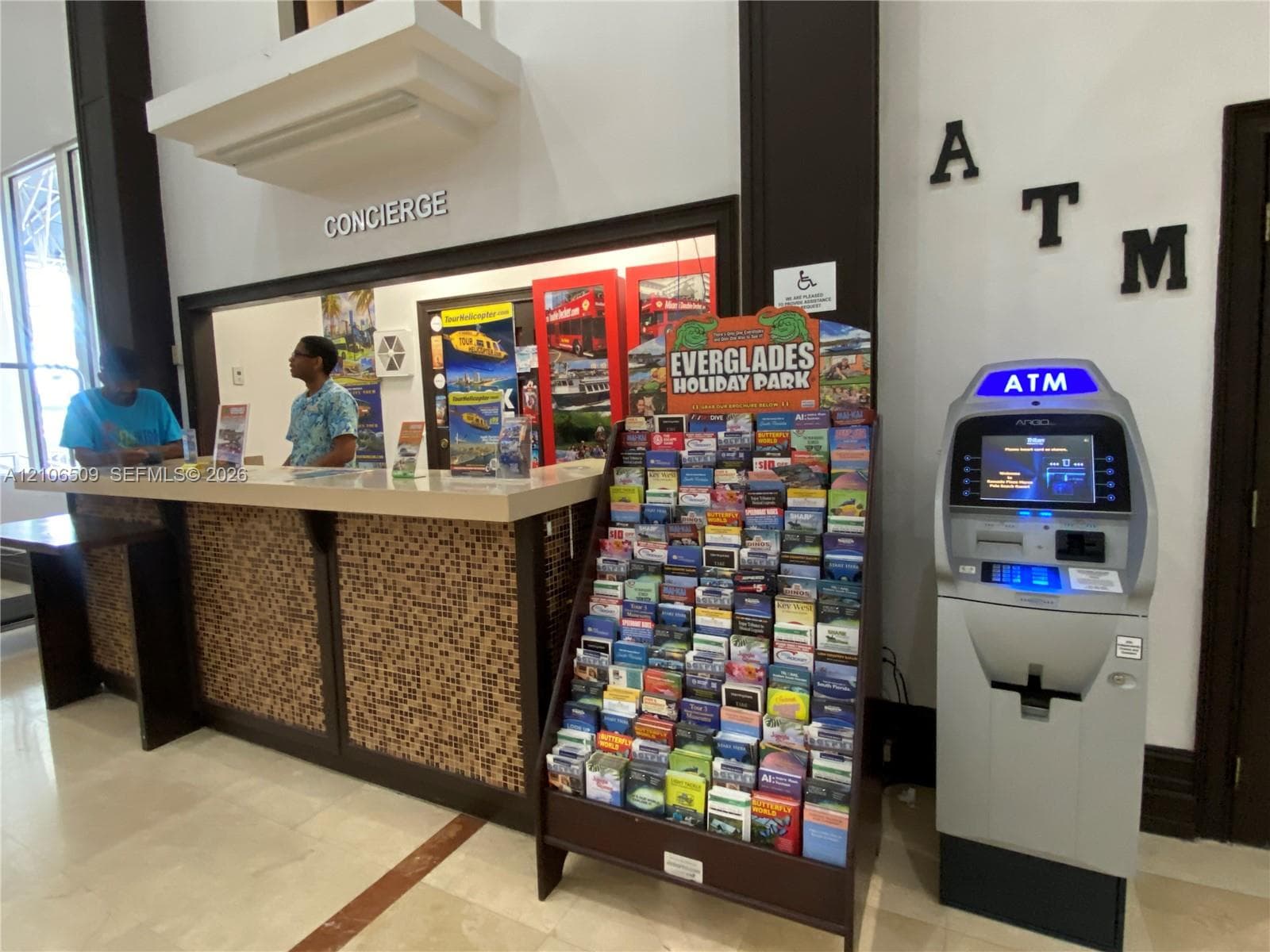 Concierge station featuring a stone-tile facade, solid surface countertop, and an automated teller machine