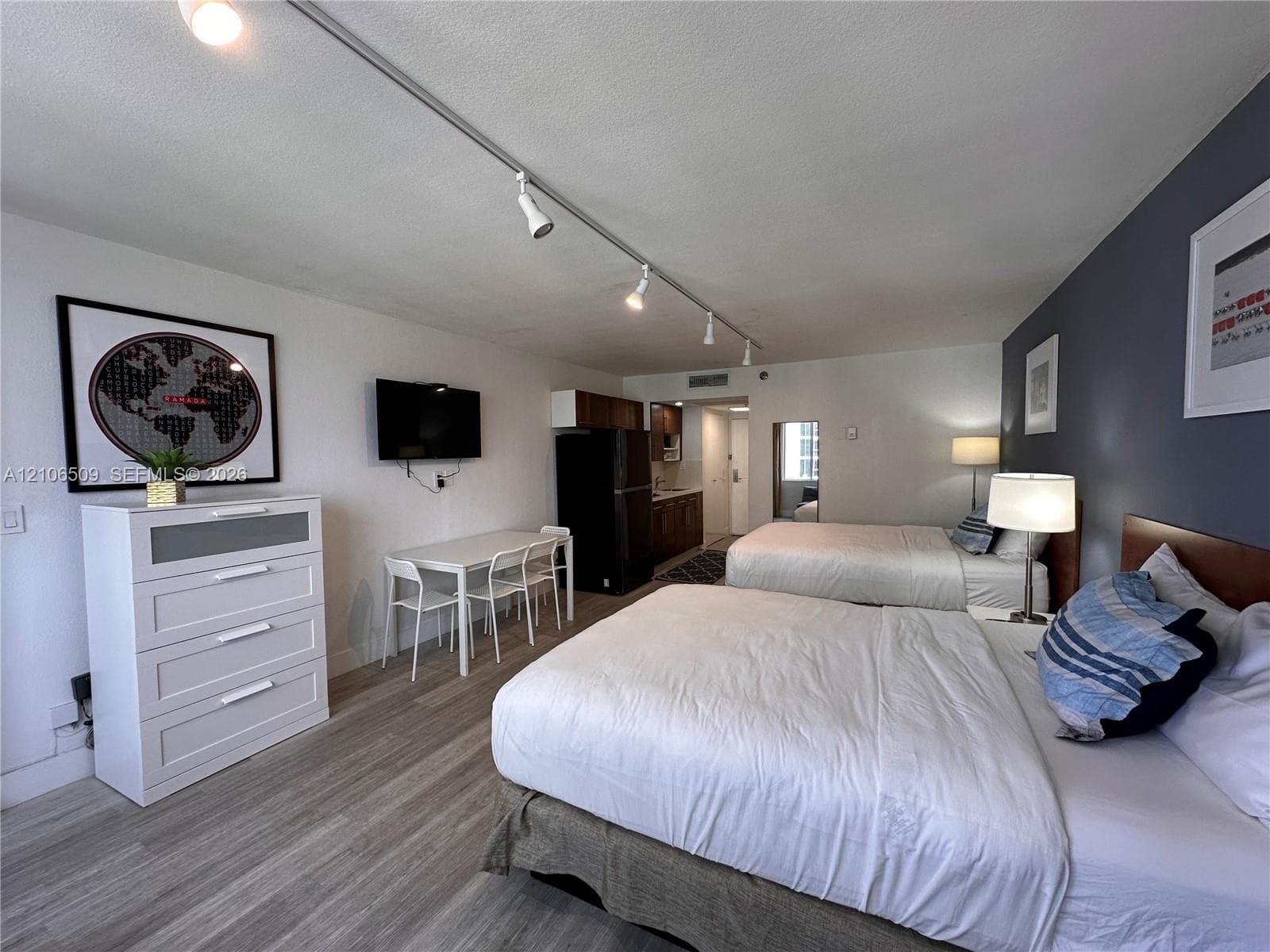 Wood-finish flooring, track lighting, and a dark-toned accent wall