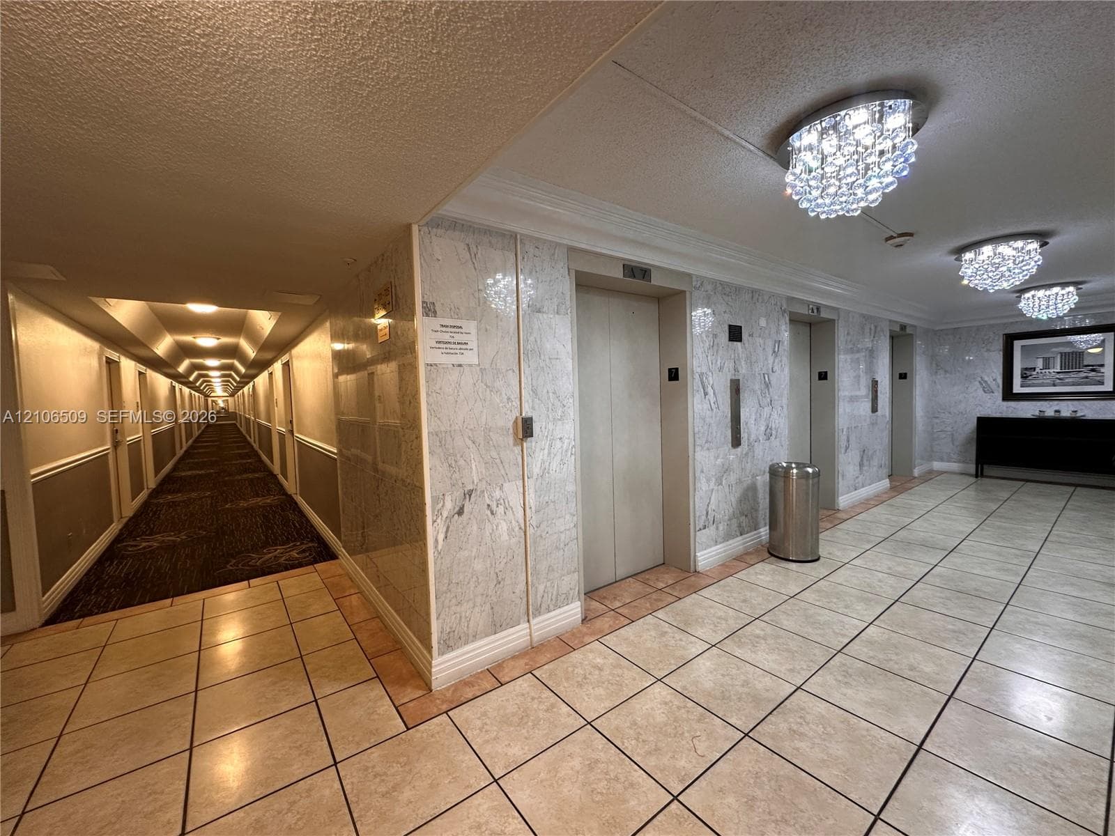 Elevator lobby featuring stone wall paneling, tile flooring, and crystal-style flush mount ceiling lighting