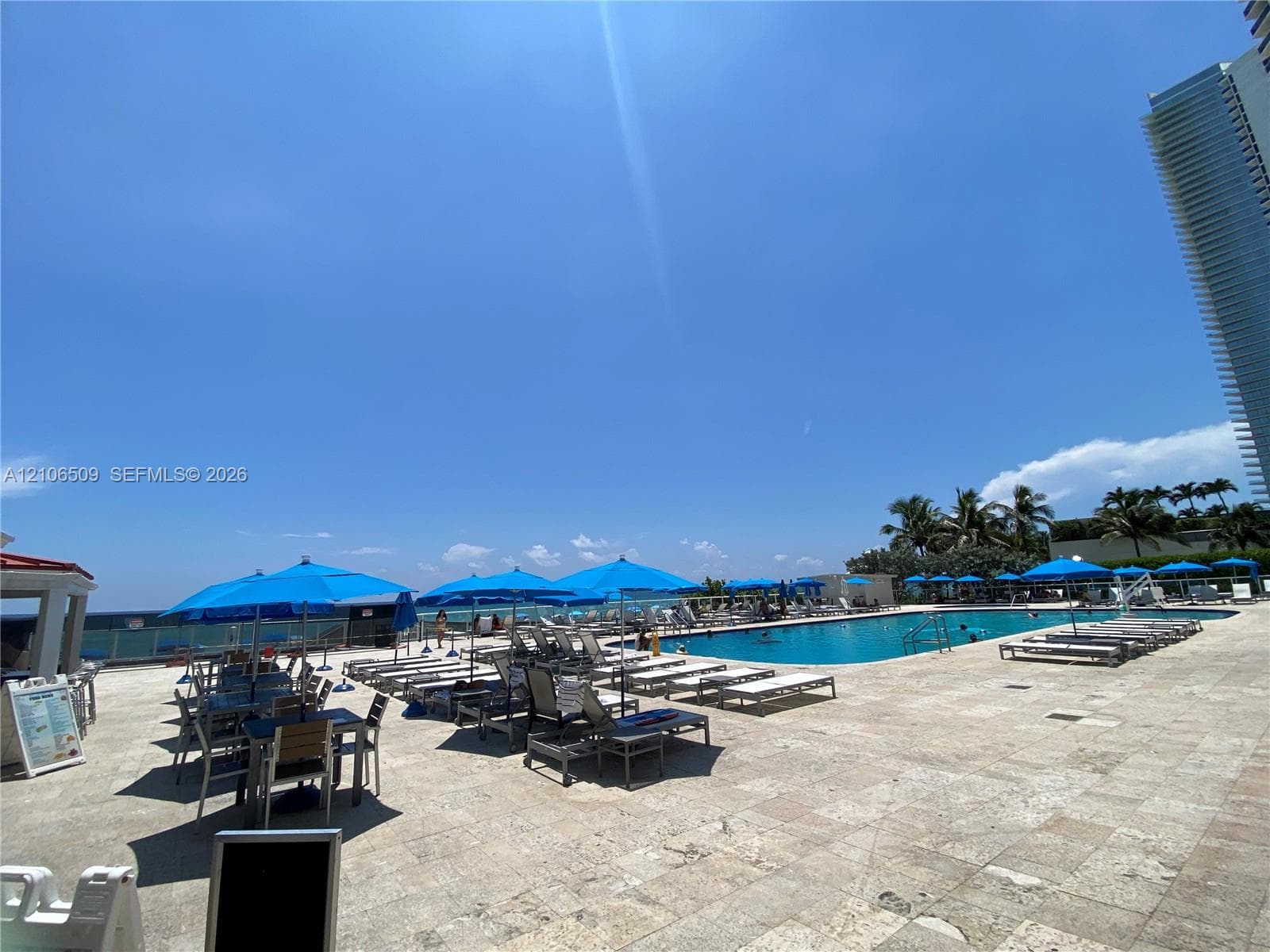 Outdoor swimming pool featuring stone deck tiling and ocean horizon backdrop