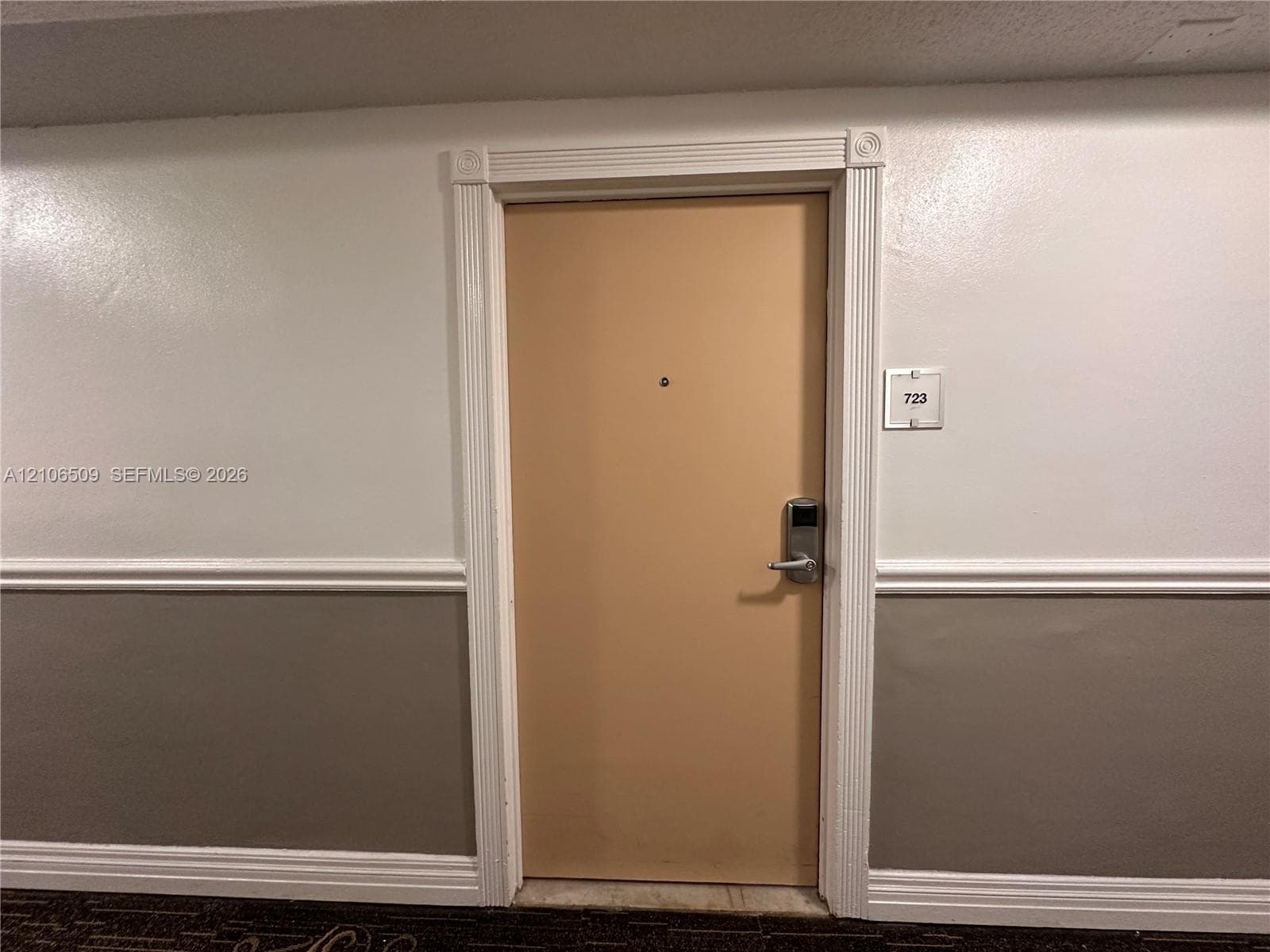 Entryway featuring a solid door with a metal electronic lock, decorative fluted casing, and a peephole, complemented by chair rail molding