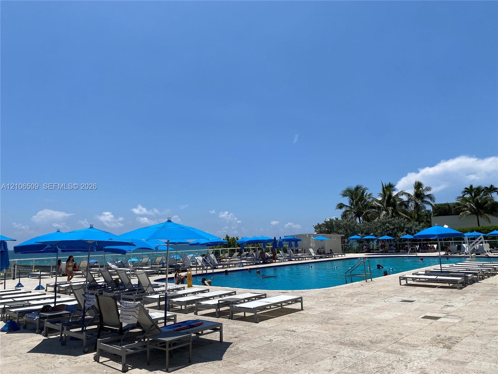 Outdoor swimming pool with stone-tiled decking, metal pool fencing, and perimeter landscaping