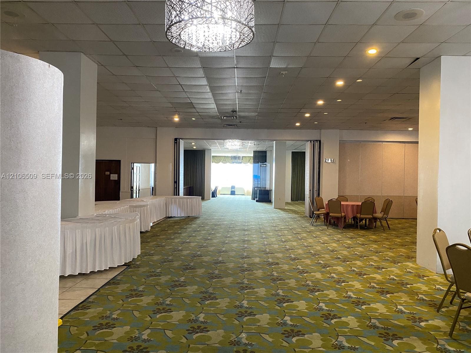 Expansive open-concept interior featuring a drop ceiling, decorative drum pendant lighting, recessed lighting, and folding accordion partition walls