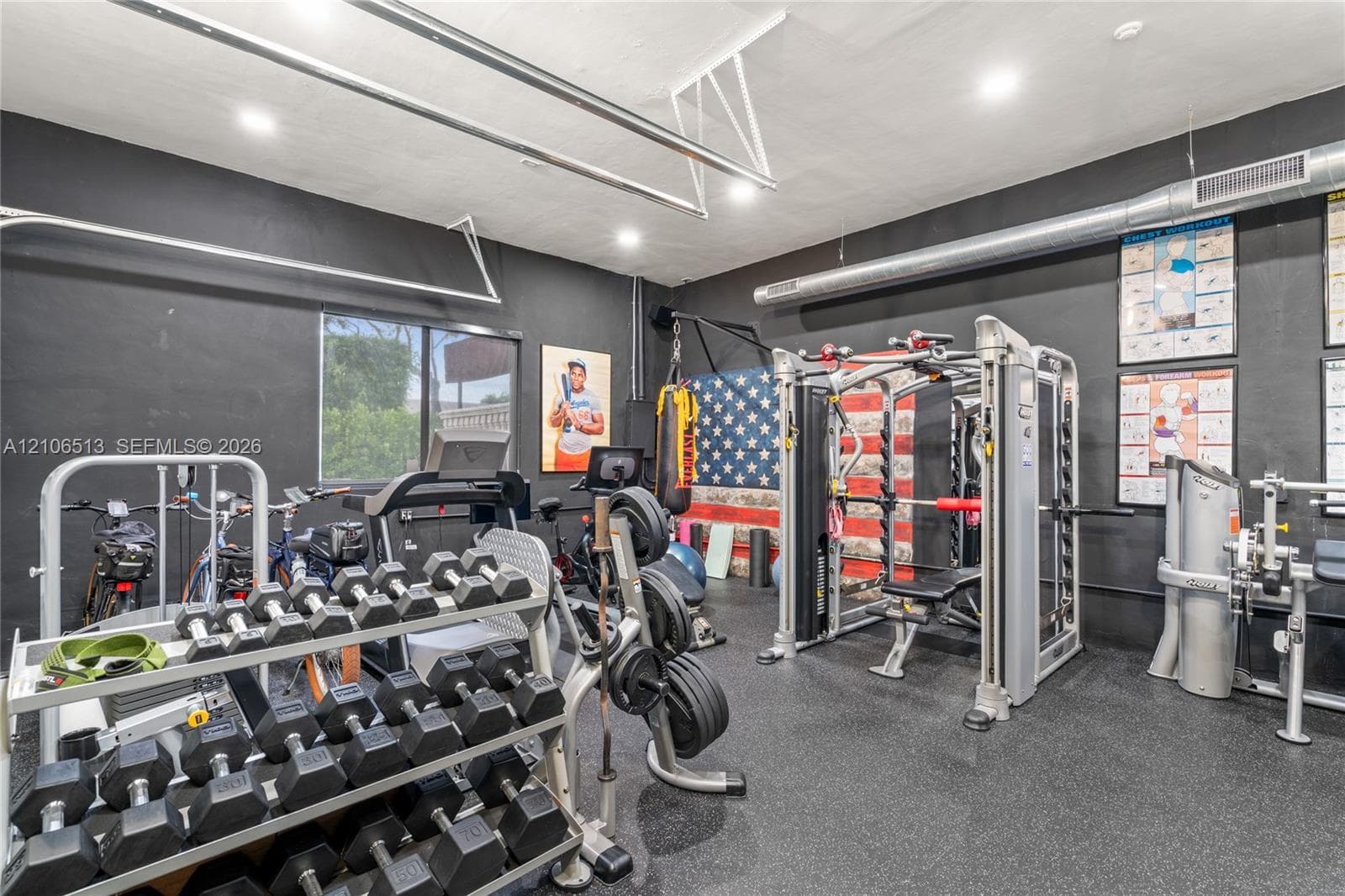 Finished garage space featuring matte black wall paint, rubberized flooring, exposed metal ductwork, and recessed lighting