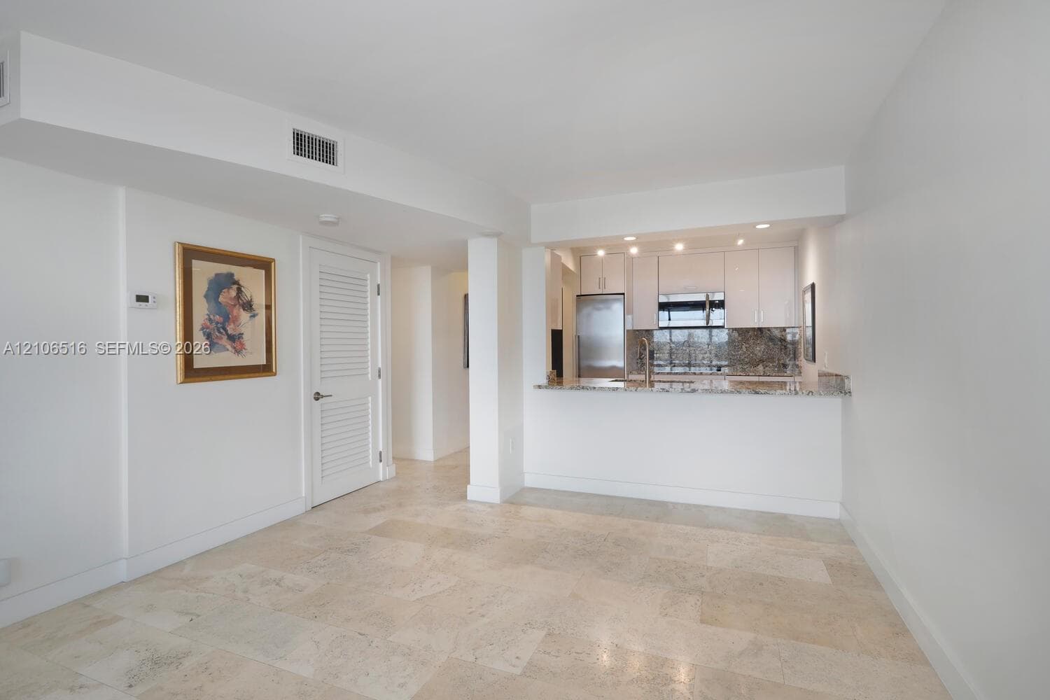 Stone tile flooring, white cabinetry, stone-finish countertops, stainless steel appliances, and recessed lighting