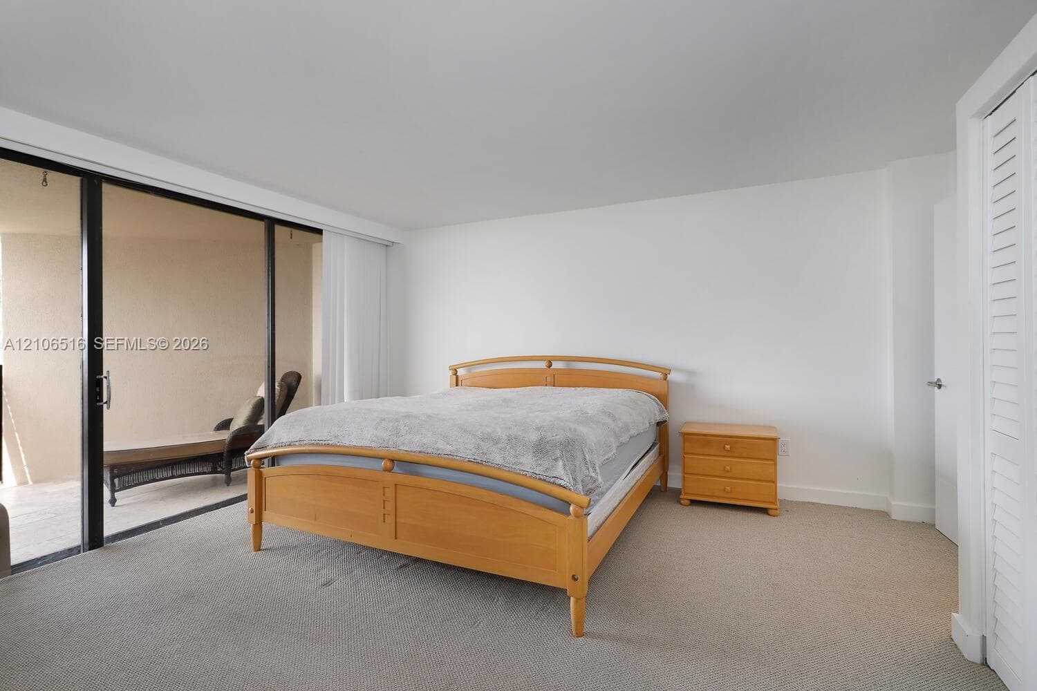 Neutral-toned carpeted flooring, floor-to-ceiling sliding glass doors, and louvered closet doors