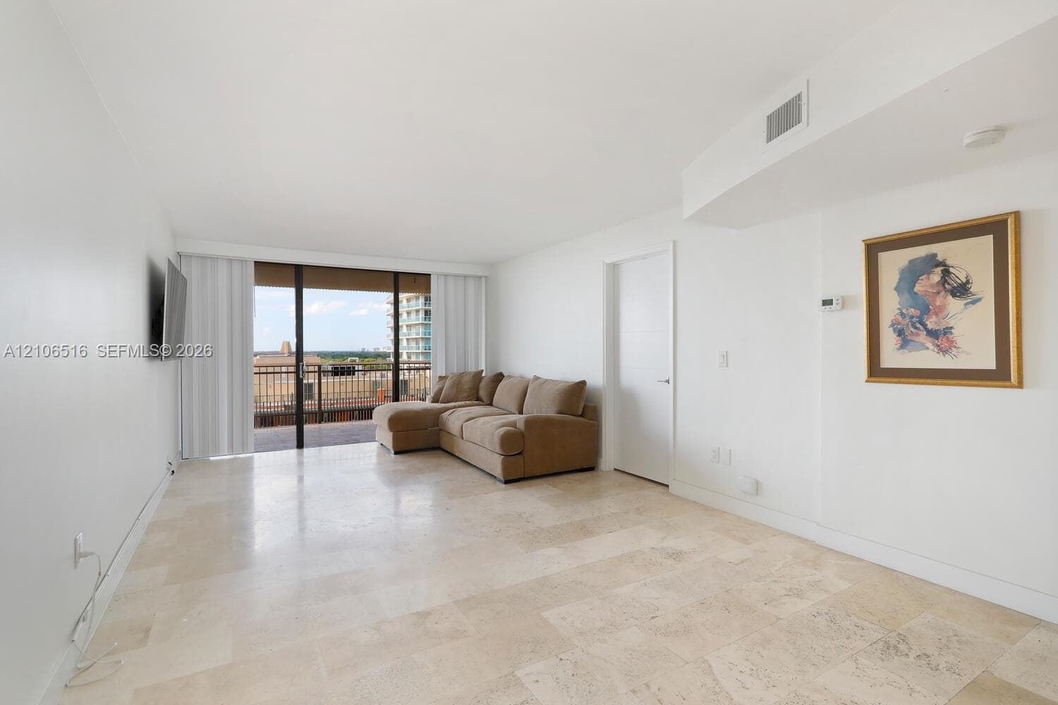 Open living area featuring large-format stone flooring, floor-to-ceiling sliding glass doors, and a private balcony