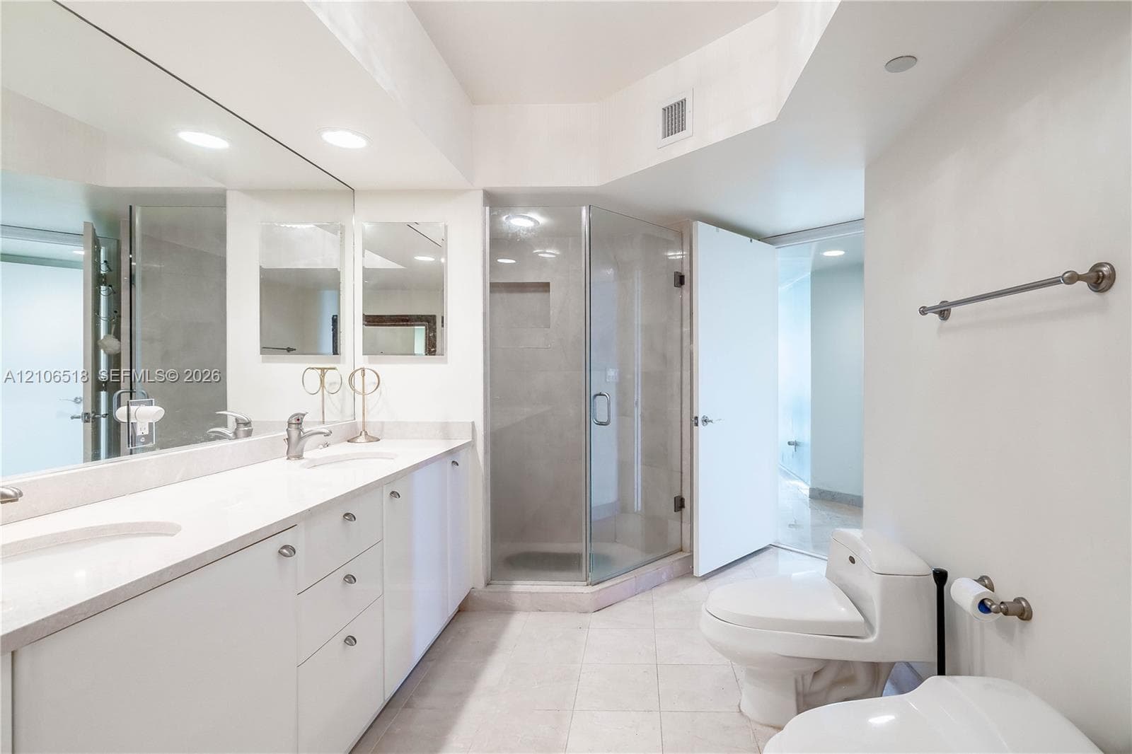 Double vanity with white cabinetry and solid-surface countertop, full-width wall mirror, glass-enclosed corner shower with tiled interior, and ceramic tile flooring