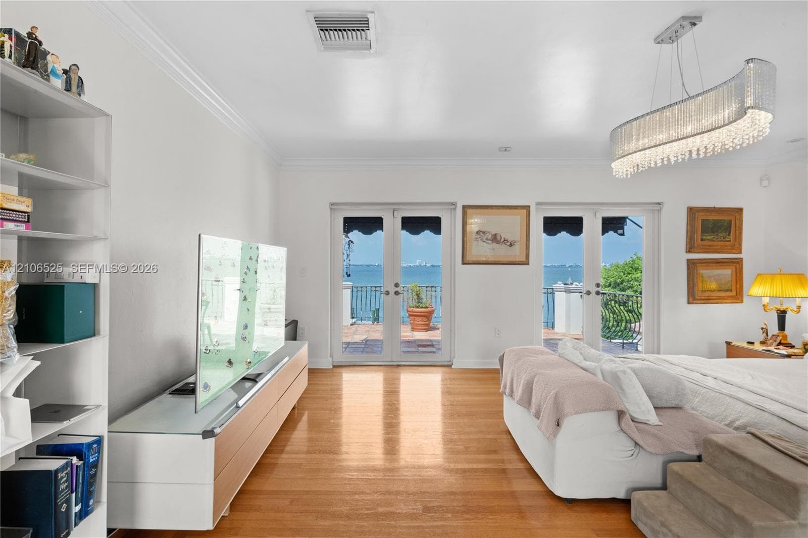 Wood-finish flooring, dual French doors, crystal-accented chandelier, and water backdrop