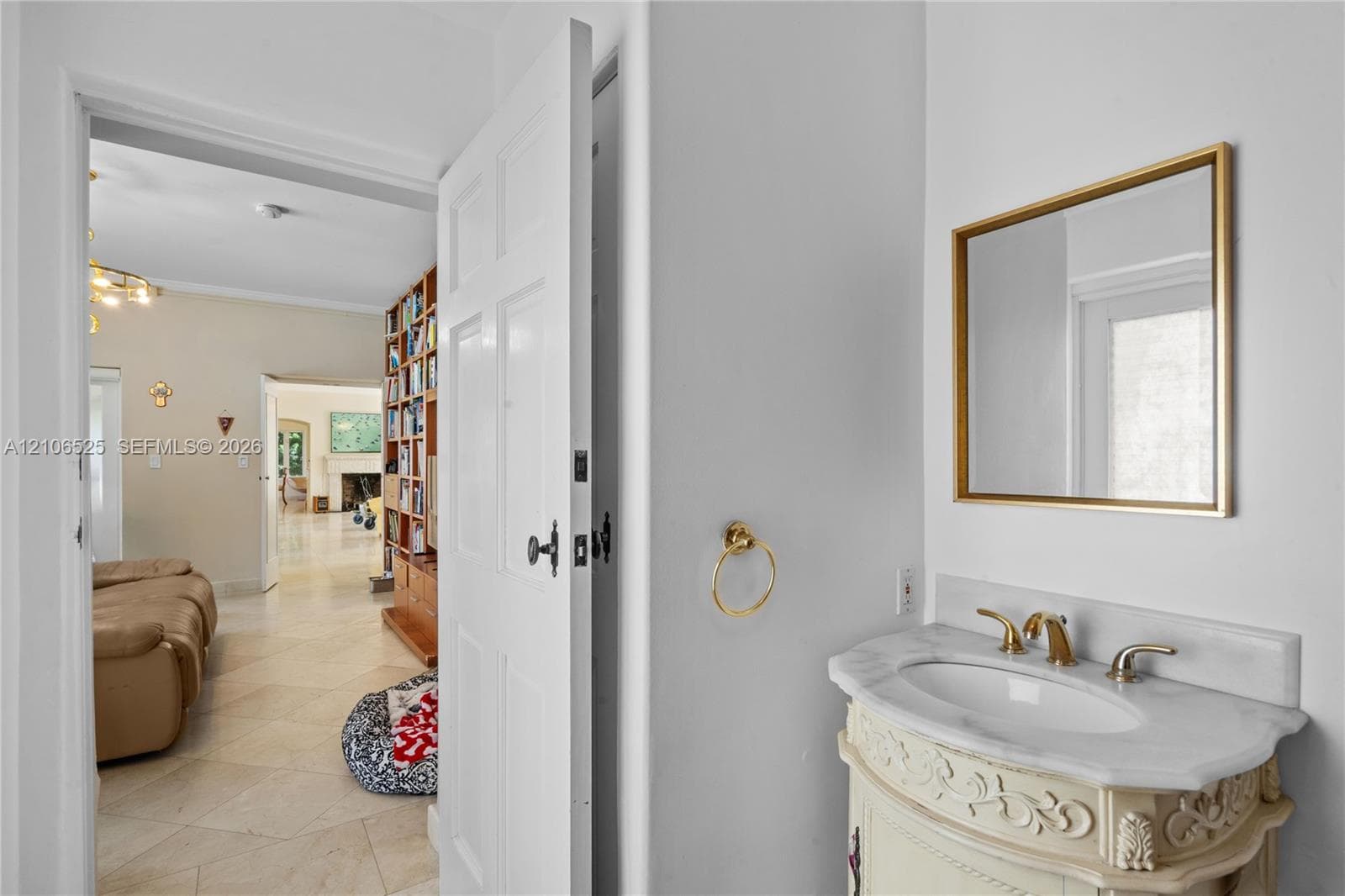 Custom vanity with an integrated stone countertop, oval undermount sink, brass finish widespread faucet, and matching brass-rimmed wall mirror