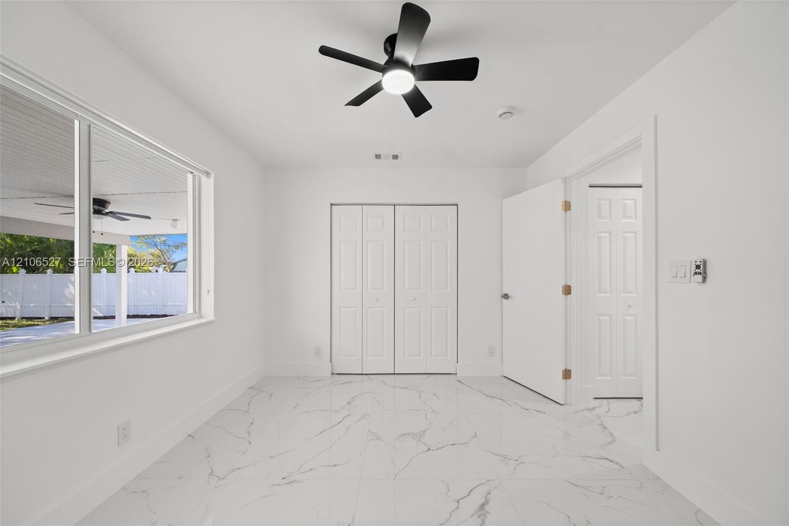 Large-format tile flooring, dual-panel closet doors, matte black ceiling fan with integrated lighting, and white interior doors
