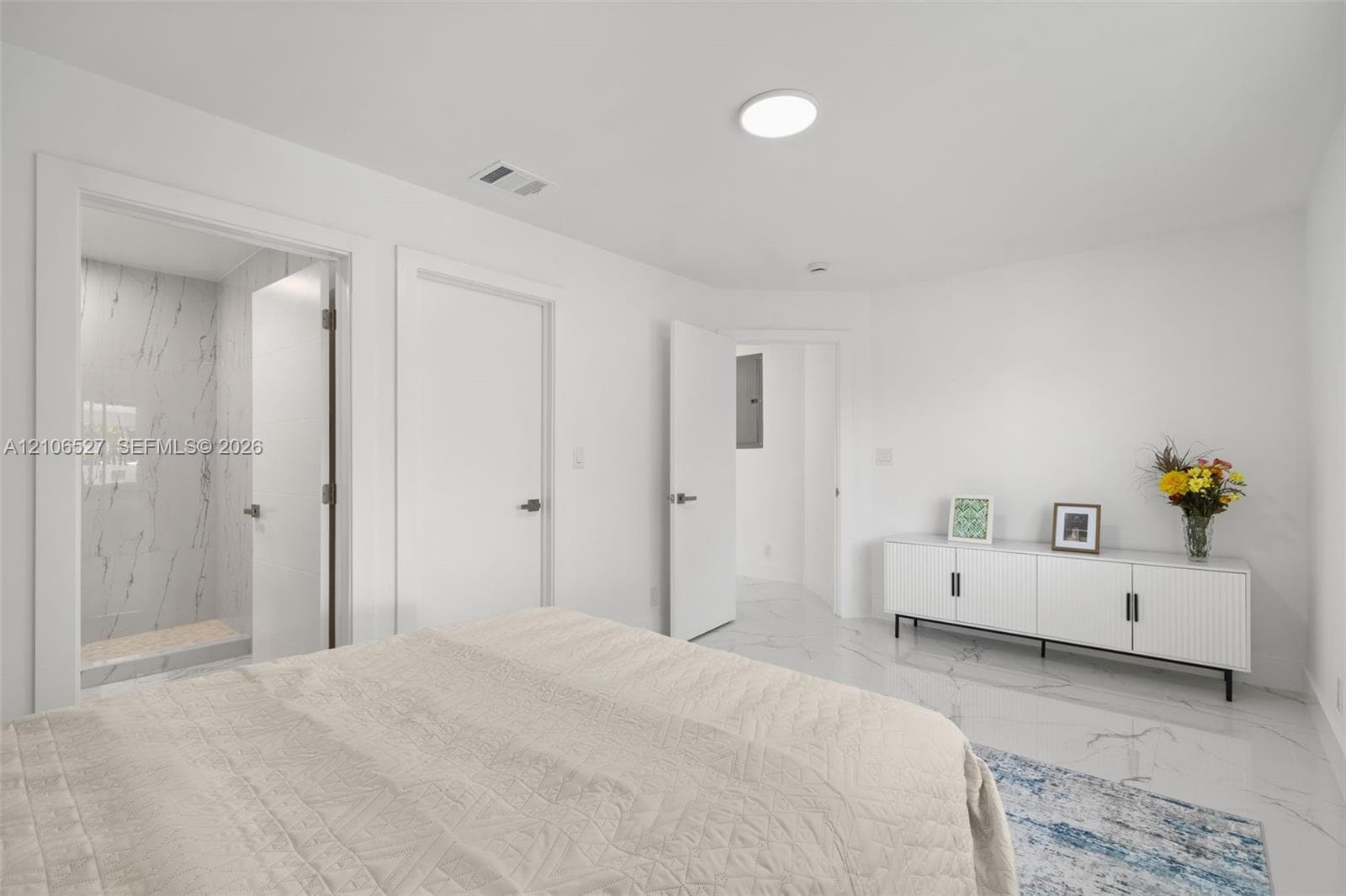 Room featuring white-finish tile flooring with gray veining, flush-mount lighting, and an enclosed shower stall with floor-to-ceiling veined tile wall surfacing