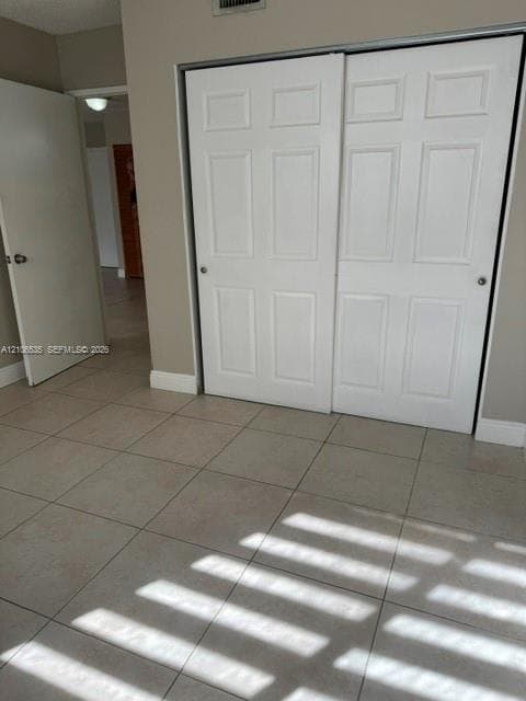 Neutral-toned ceramic tile flooring, two-panel interior passage door, and white six-panel sliding closet doors