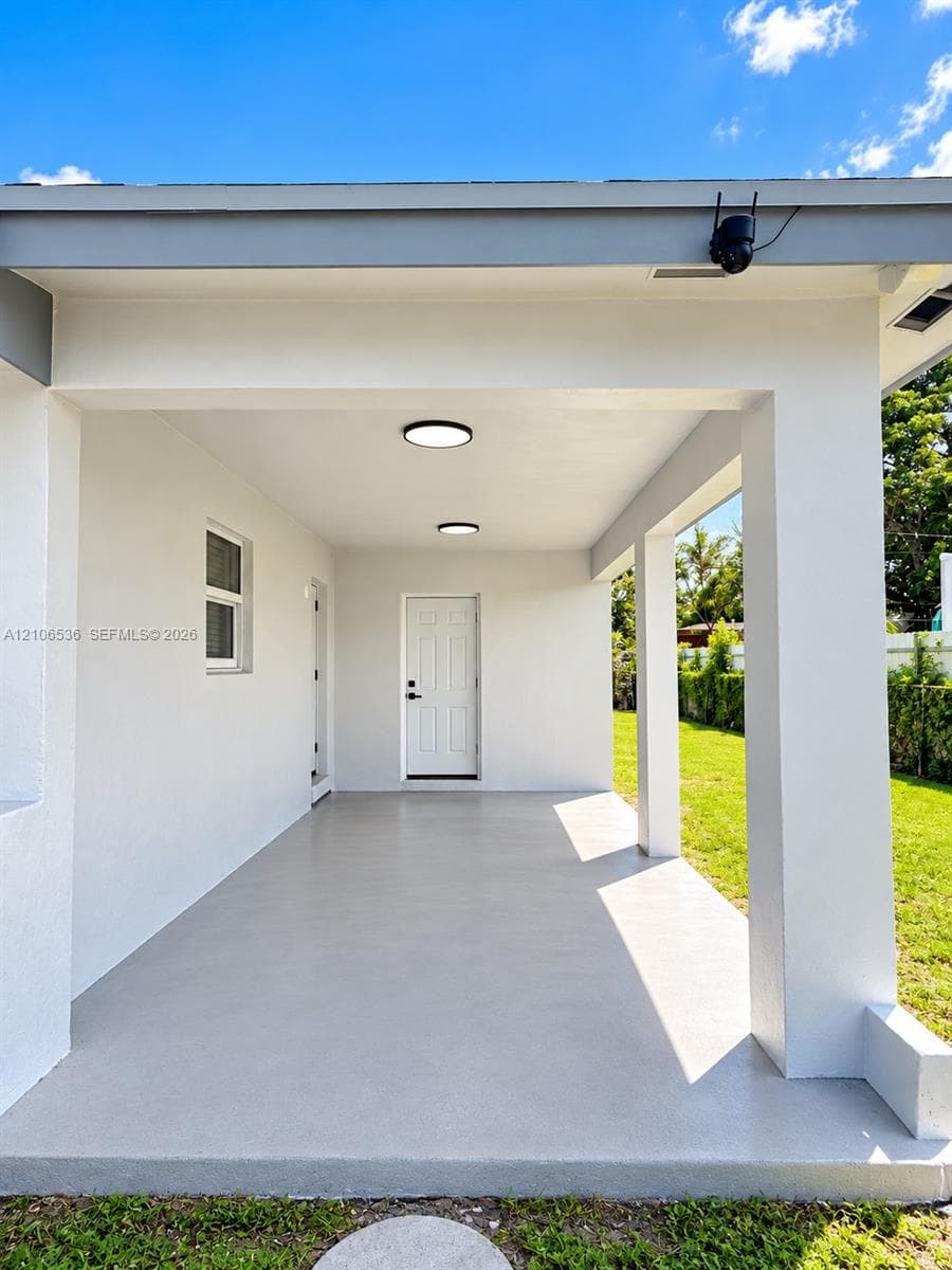 Covered patio featuring a smooth concrete floor, recessed lighting, square structural columns, and a solid-core exterior door
