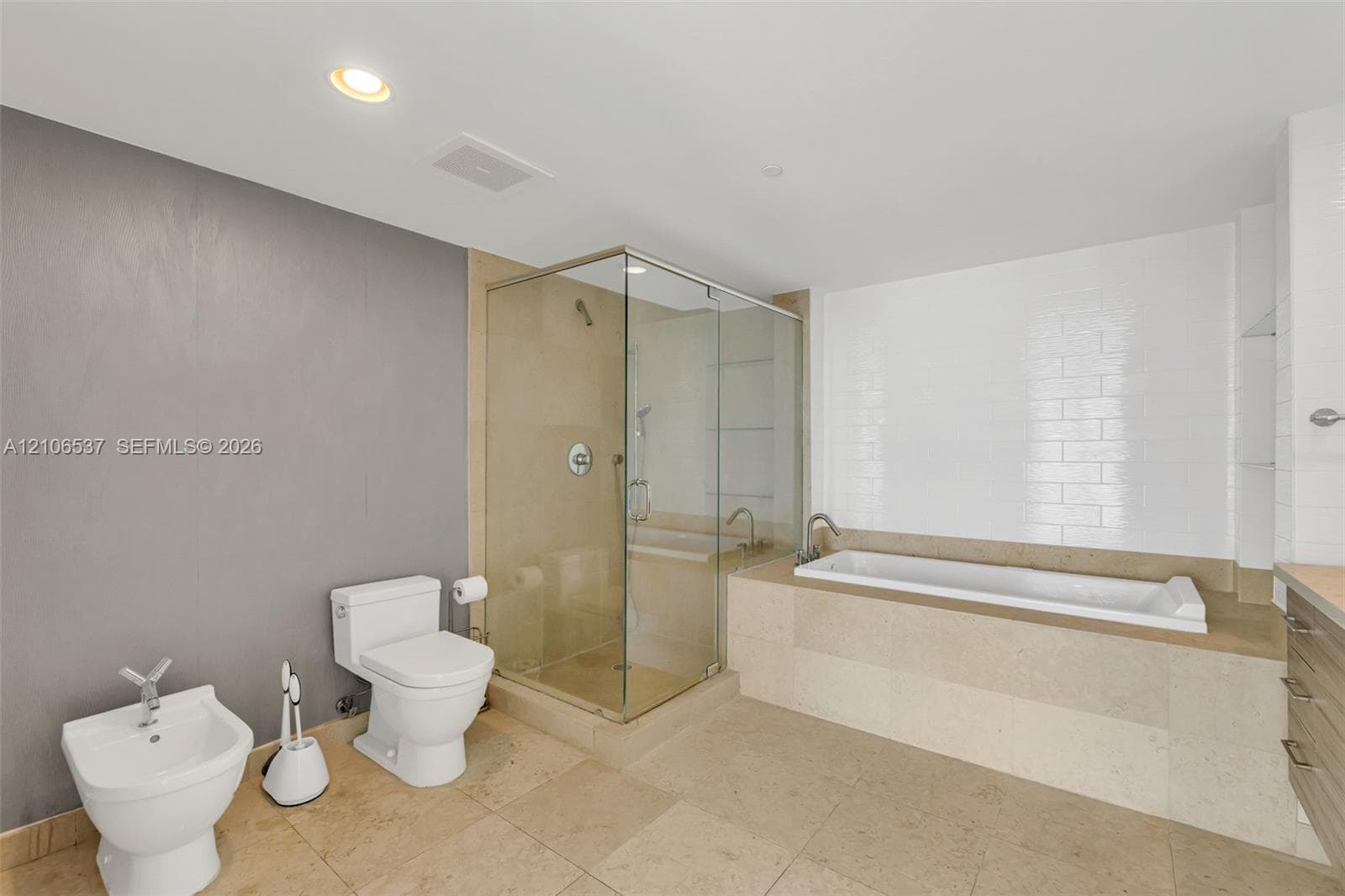 Bathroom featuring a glass-enclosed shower, a deep soaking tub with tile surround, porcelain tile flooring, and a bidet