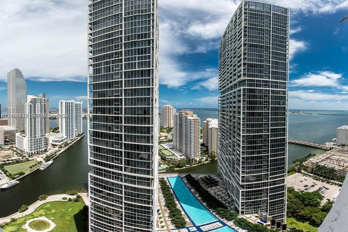 High-rise residential towers featuring floor-to-ceiling glass facades, a linear outdoor swimming pool, and a waterfront location