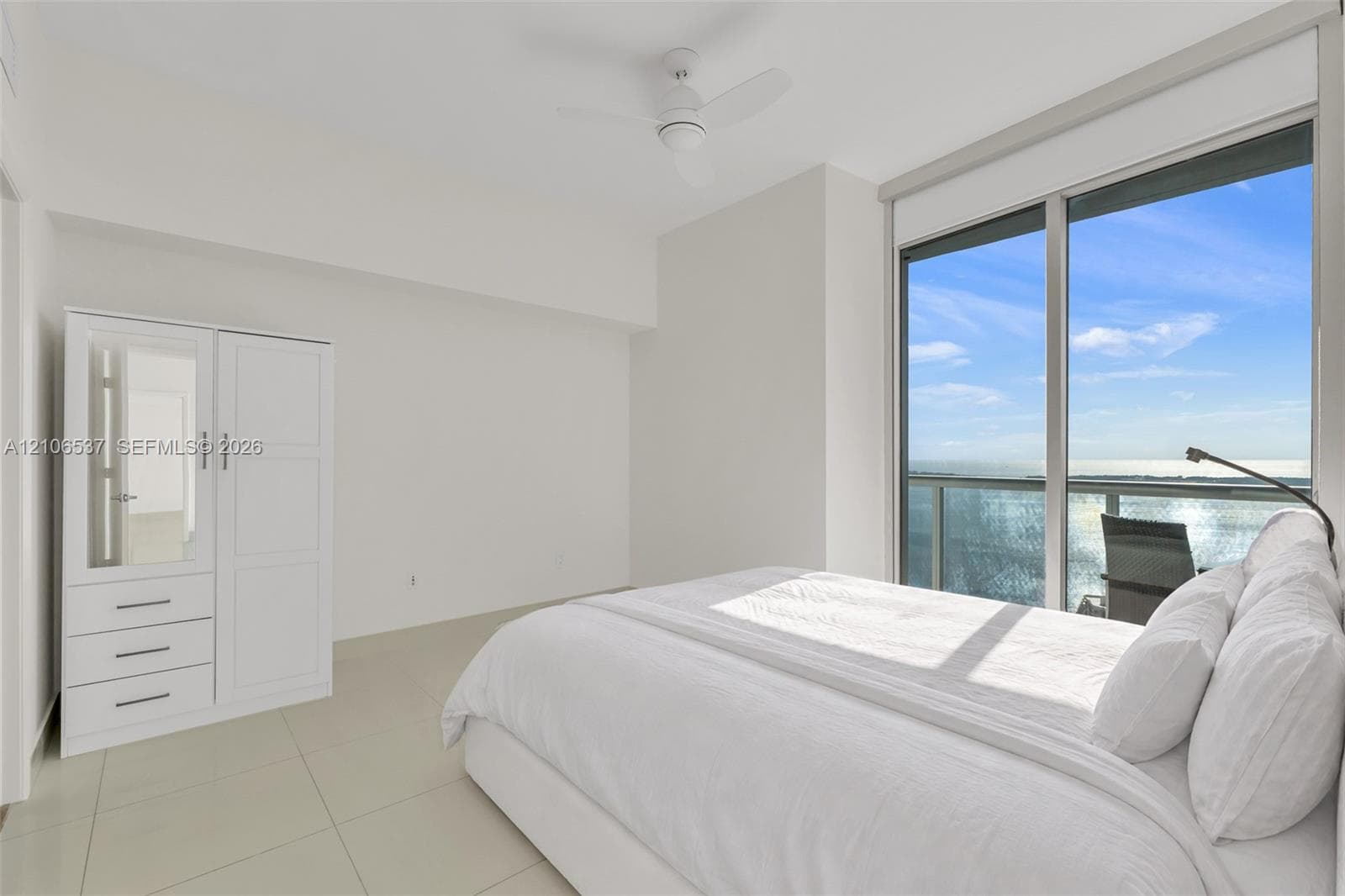 Floor-to-ceiling sliding glass doors, neutral tile flooring, built-in white cabinetry, and a ceiling-mounted fan