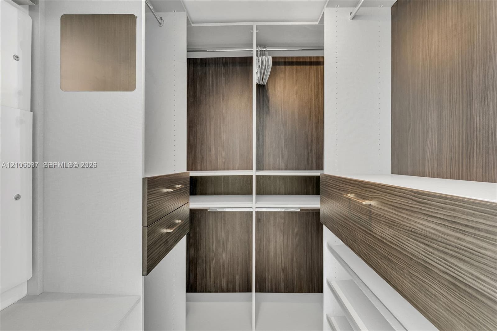Custom closet system featuring wood-finish cabinetry, built-in shelving, integrated hanging rods, and drawers with metallic hardware