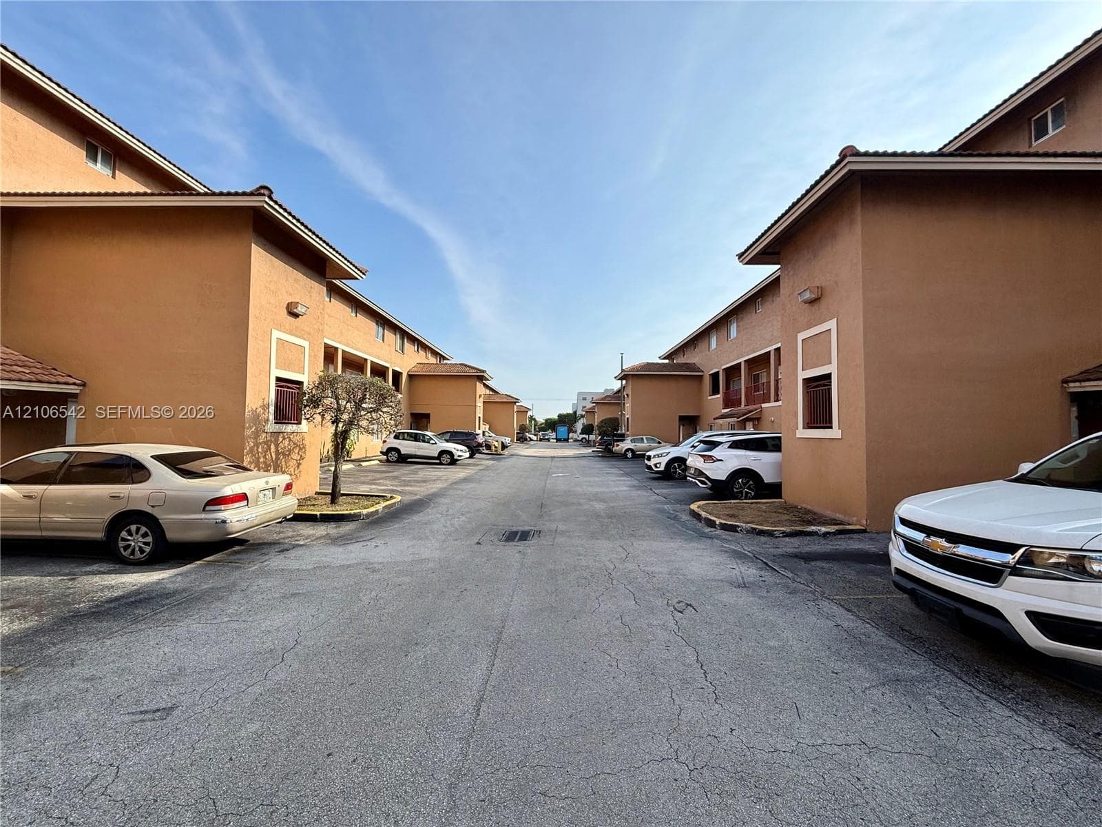 Stucco exterior complex featuring tiled roofing and designated surface parking areas