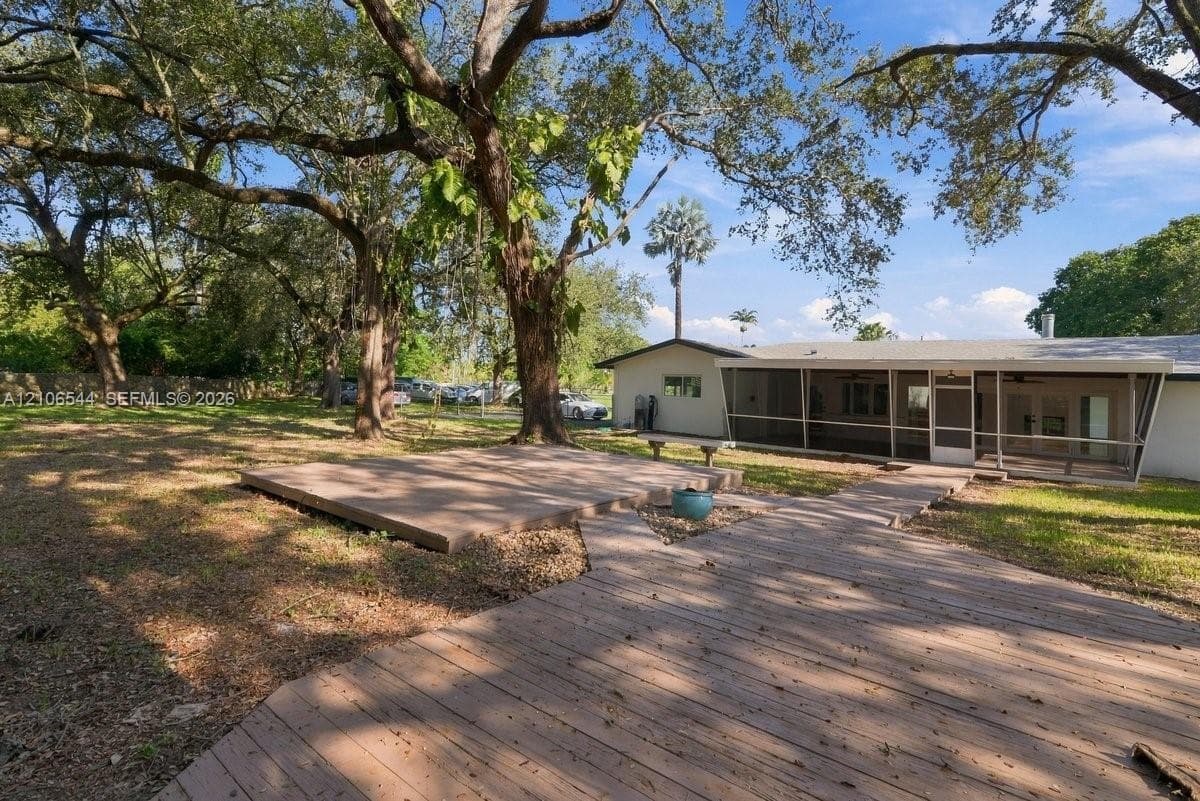 Expansive backyard featuring mature shade trees, tiered wood decking, and a screened-in porch