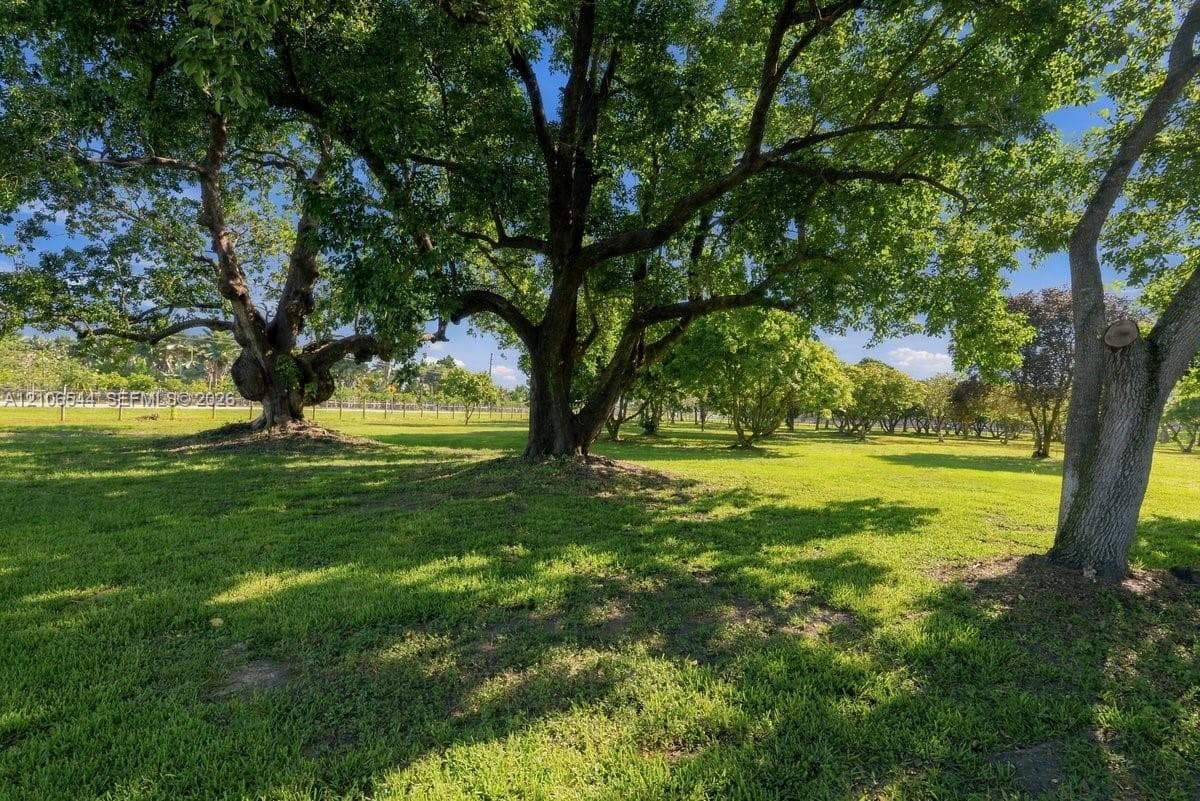 Expansive grounds featuring mature shade trees, a manicured lawn, and post-and-wire perimeter fencing