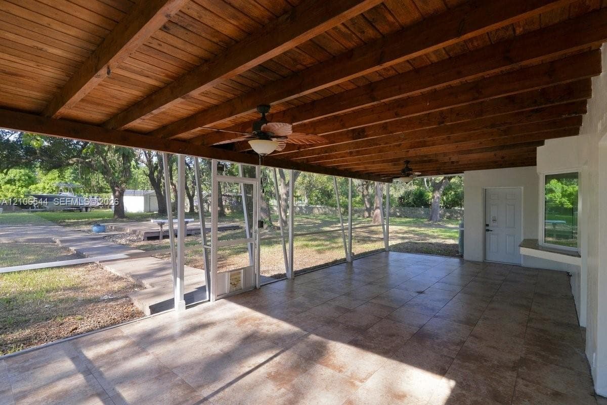 Screened-in patio featuring a wood-beam ceiling, tiled flooring, built-in ceiling fans, and a partial glass-pane exterior door