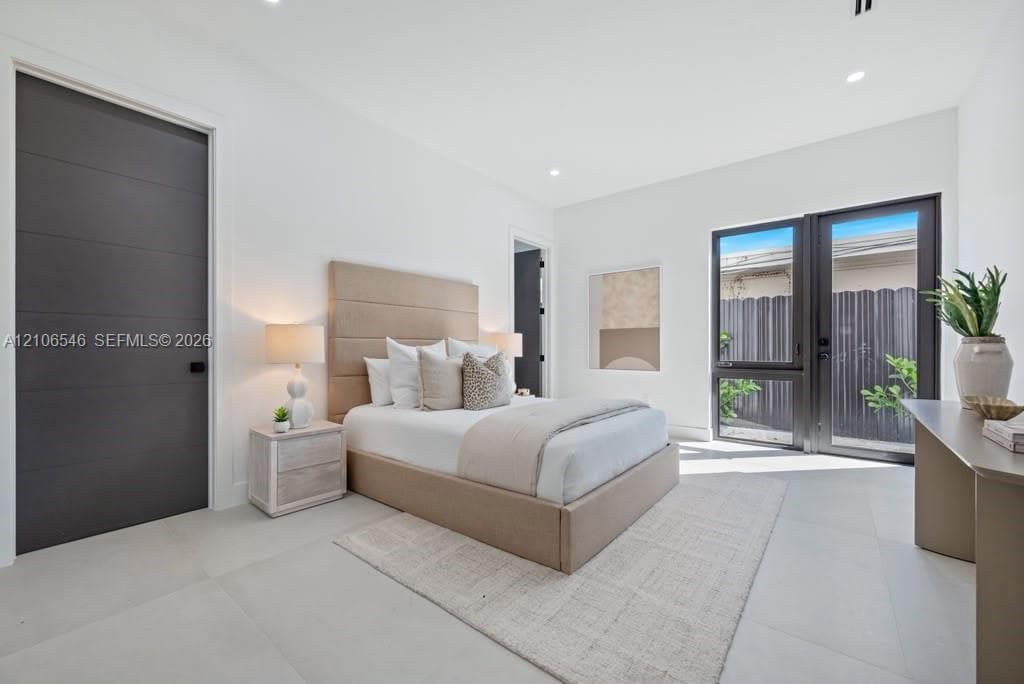 Neutral-toned room featuring expansive large-format floor tile, matte-finish horizontal panel doors, high ceilings, and floor-to-ceiling glass panel doors