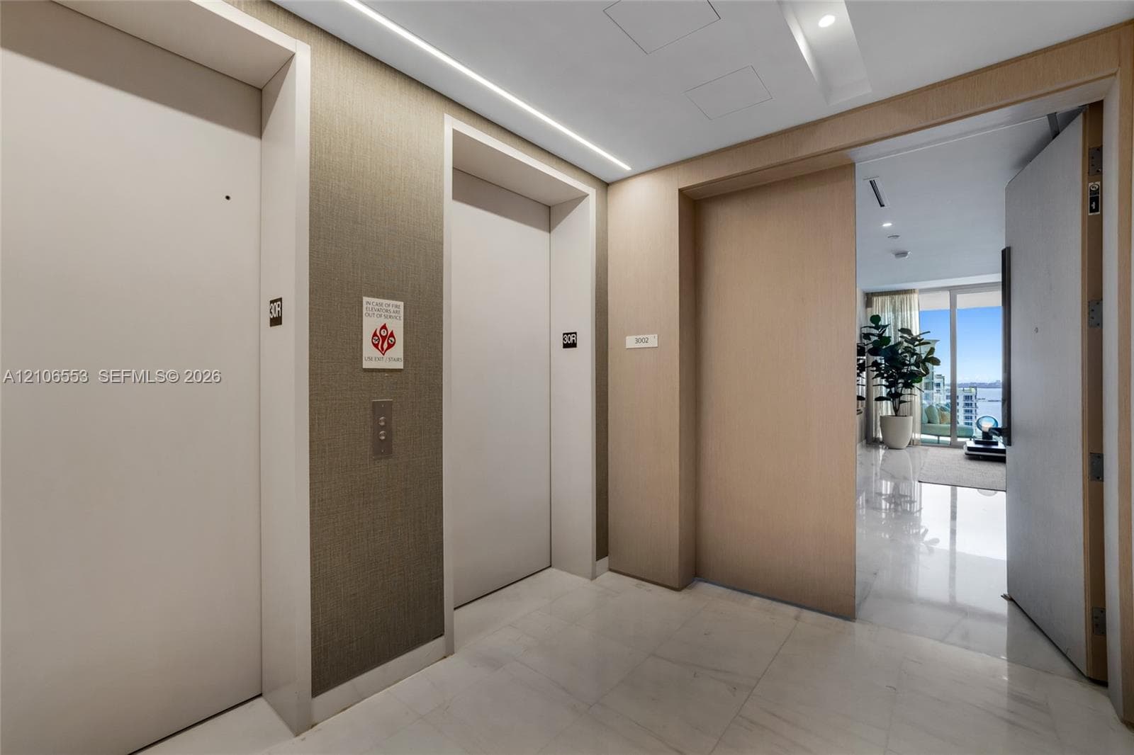 Private elevator landing featuring stone flooring, textured wall coverings, and integrated recessed ceiling lighting