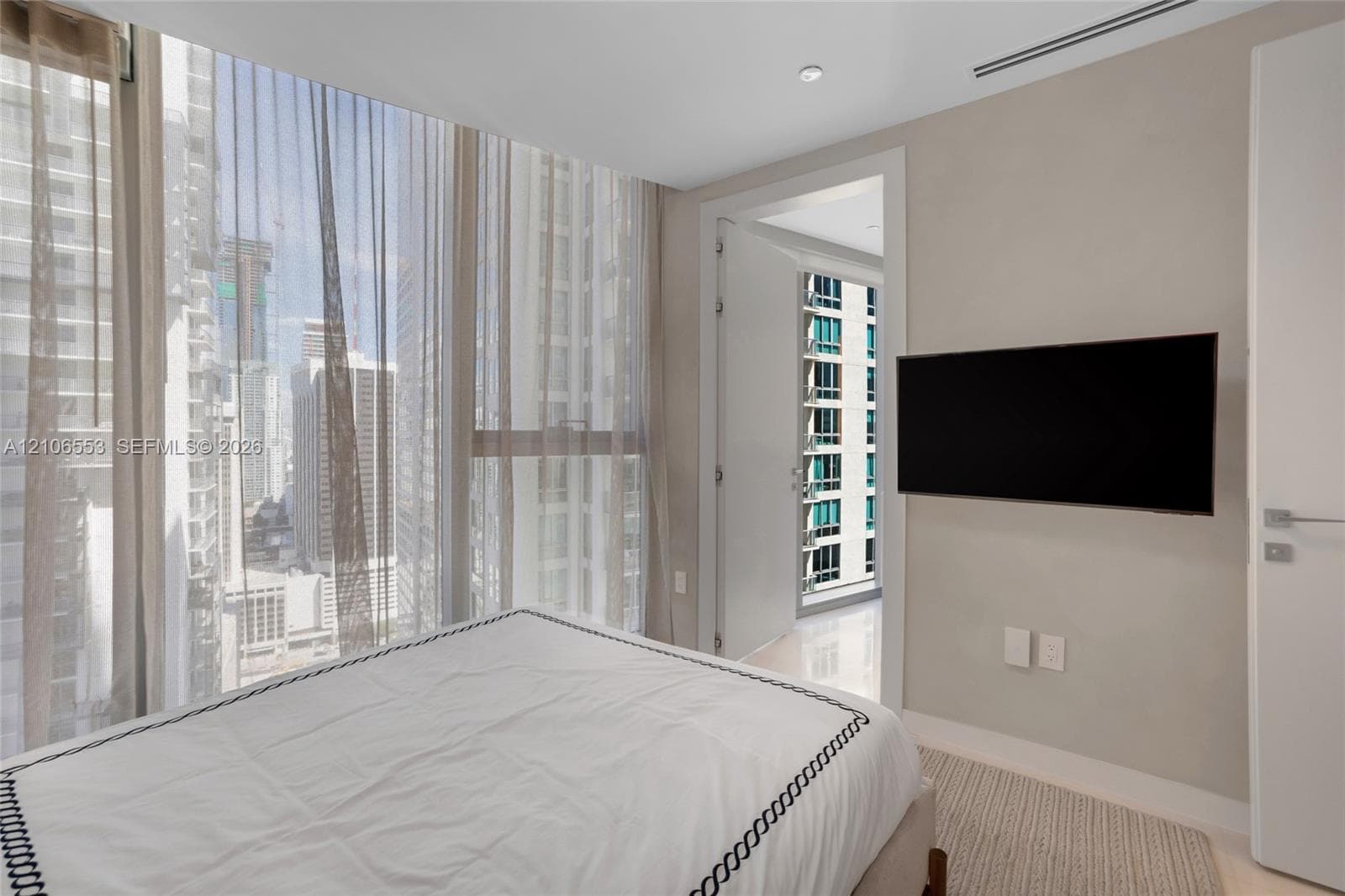 Floor-to-ceiling windows, polished stone flooring, recessed ceiling lighting, and wall-mounted television hardware