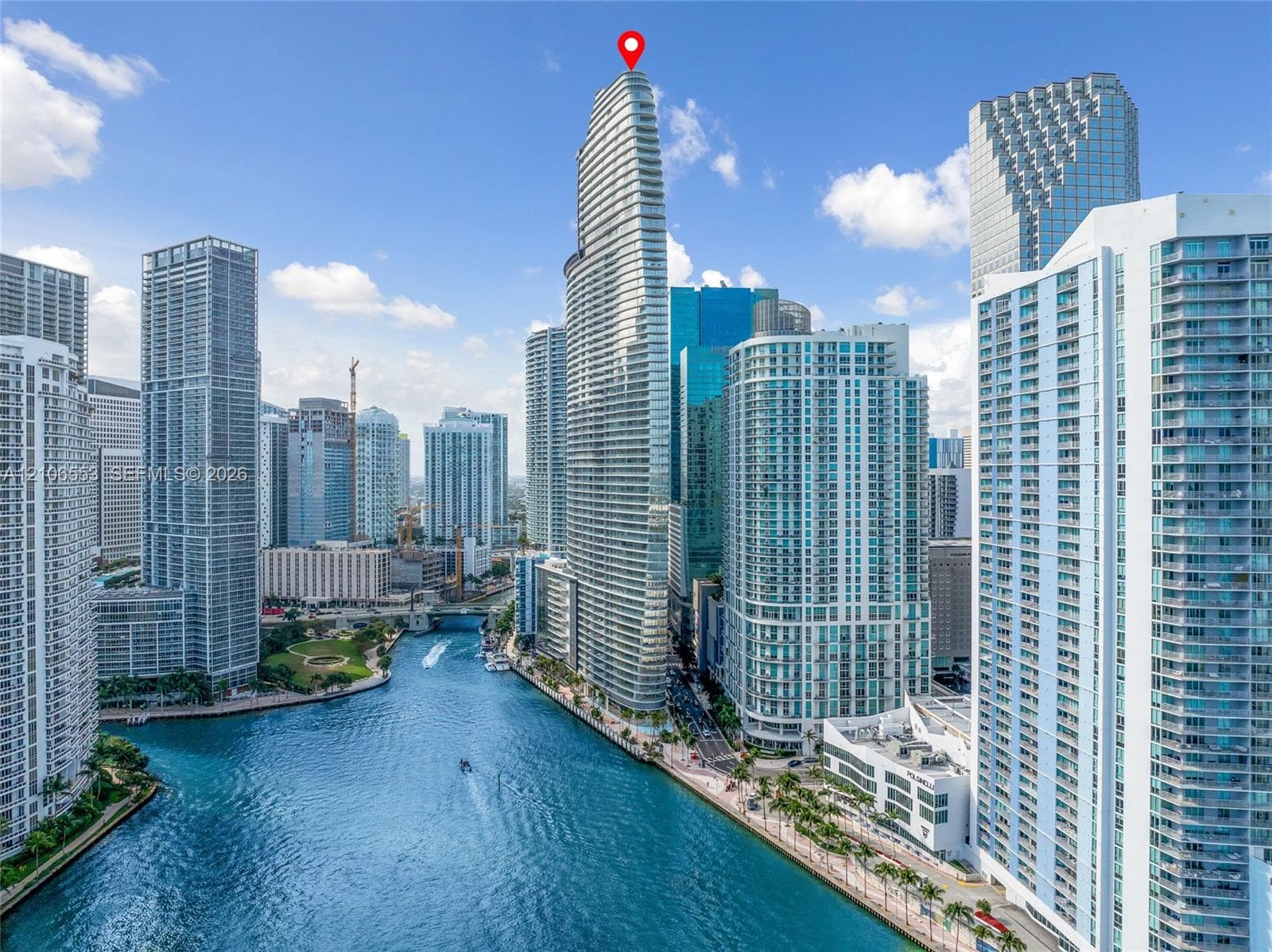 High-rise glass facade residential tower featuring a prominent tapered architectural design, located on a waterfront parcel with direct canal access