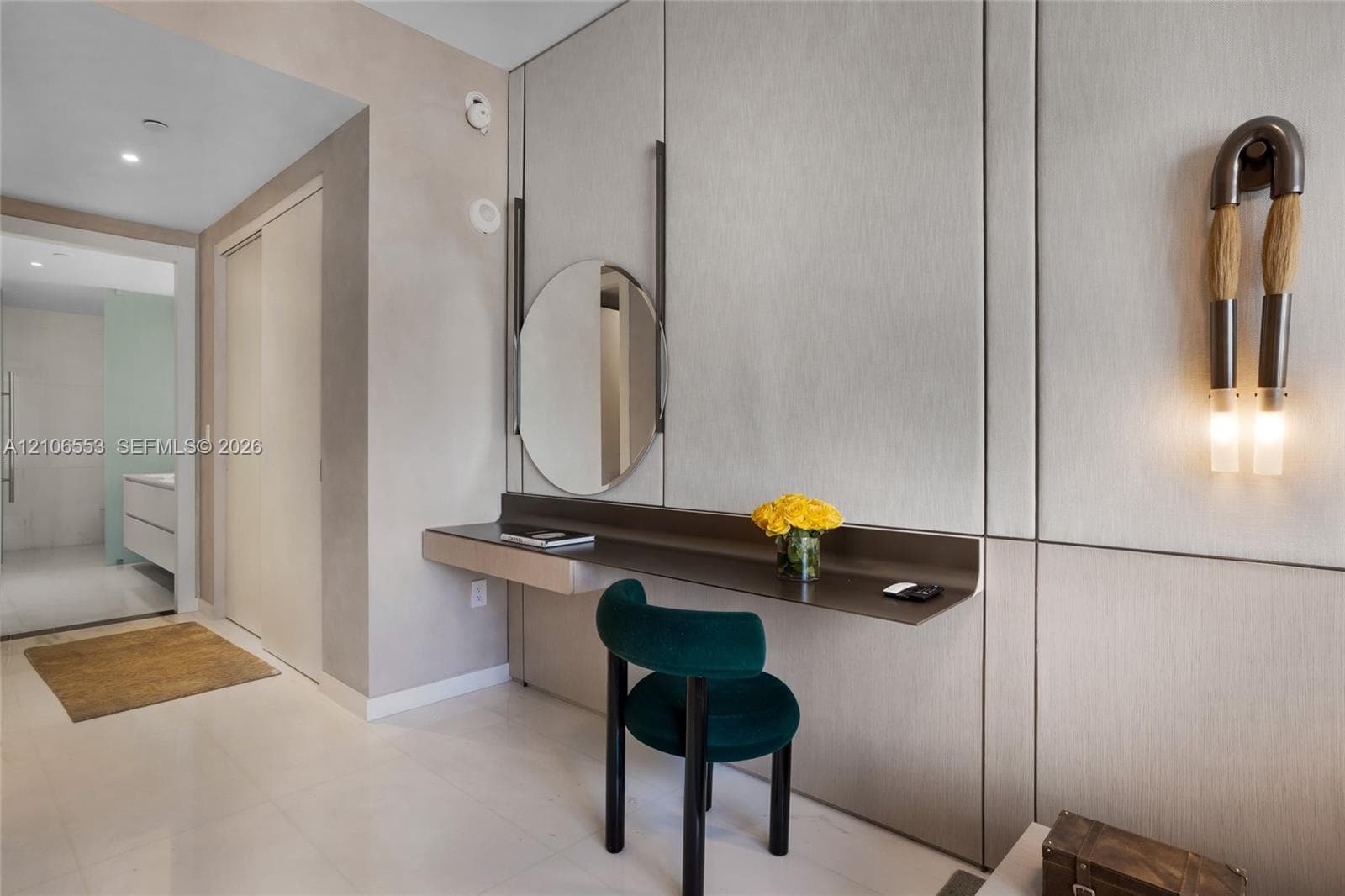 Built-in floating desk with integrated shelving, wall-mounted circular mirror, full-height paneled wall cladding, and contemporary vertical wall sconces