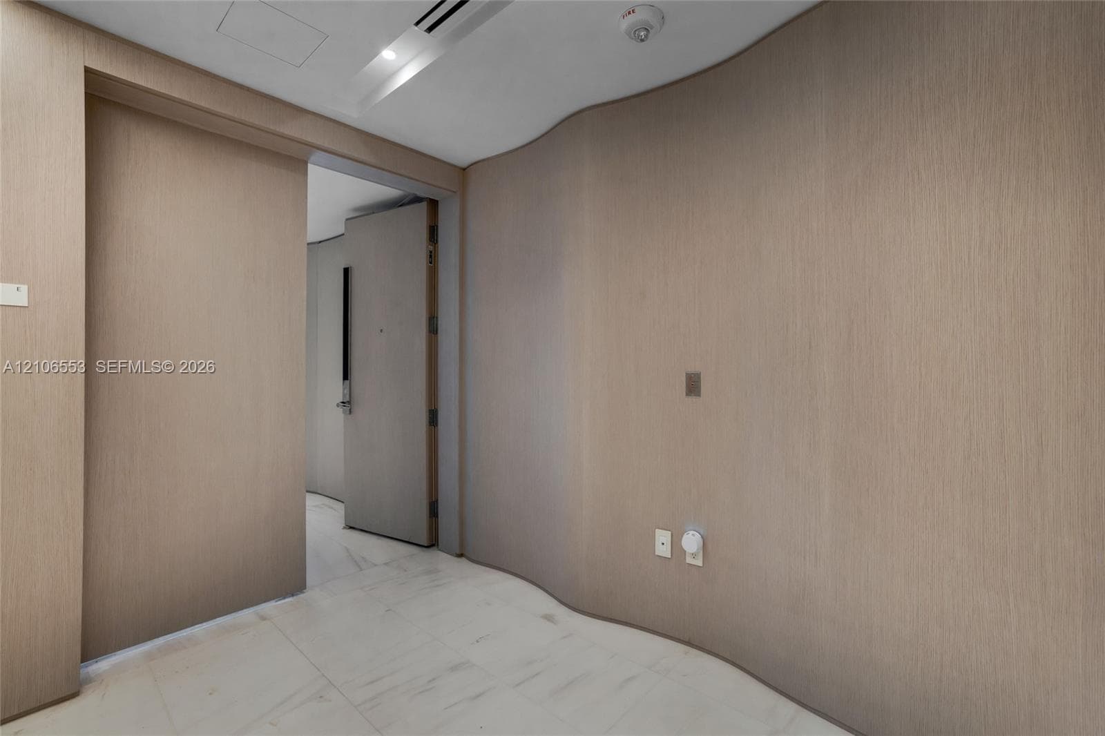 Curved wood-finish wall paneling, full-height sliding door, and stone-finish flooring