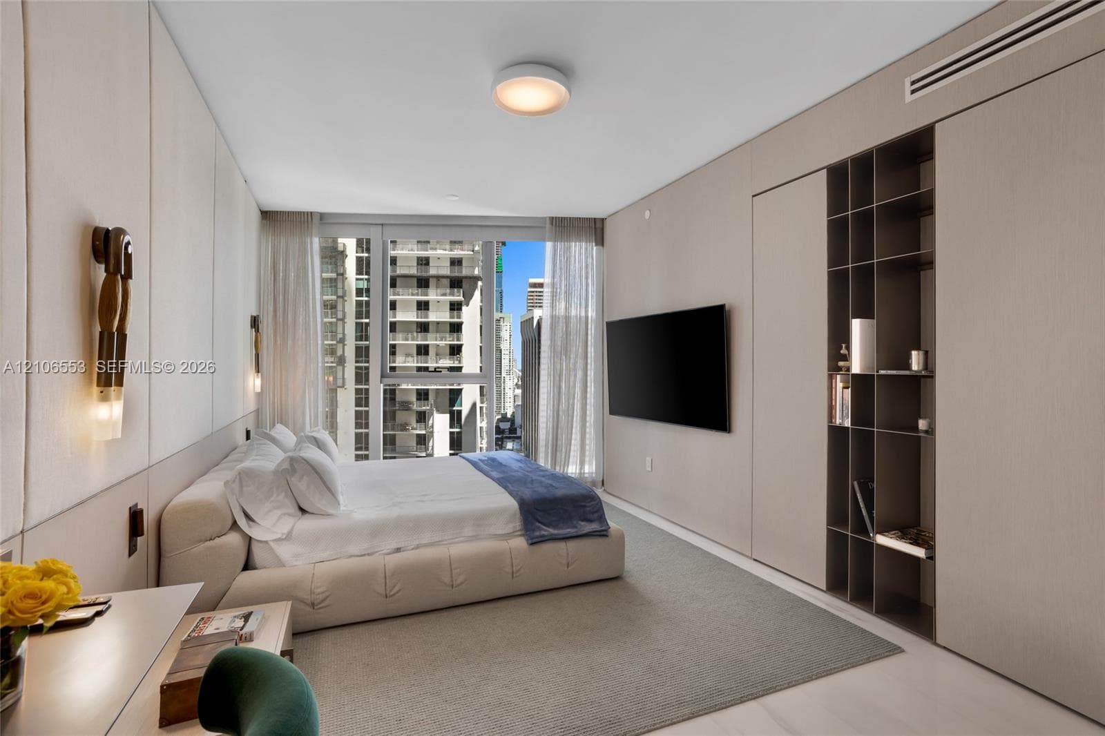 Wall-to-wall integrated cabinetry with open shelving, floor-to-ceiling windows, neutral upholstered wall paneling, and dual contemporary wall-mounted light fixtures