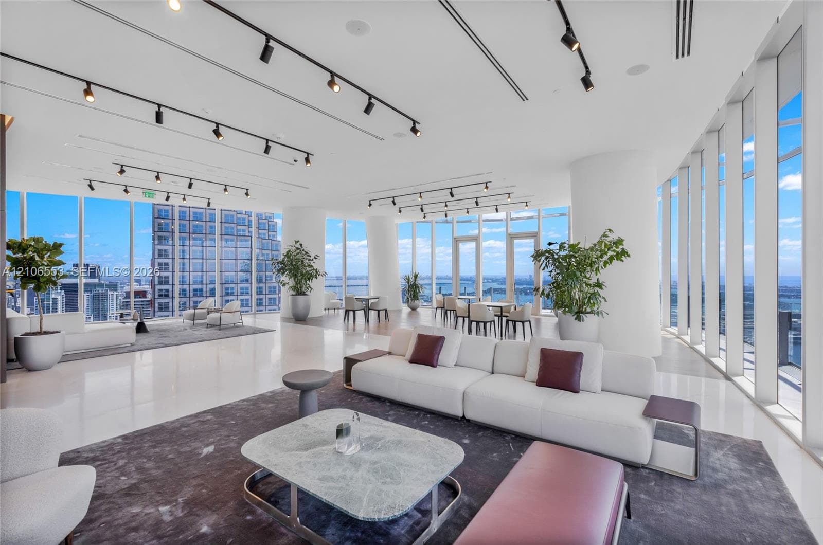 Expansive interior space featuring floor-to-ceiling windows, polished stone flooring, and adjustable overhead track lighting