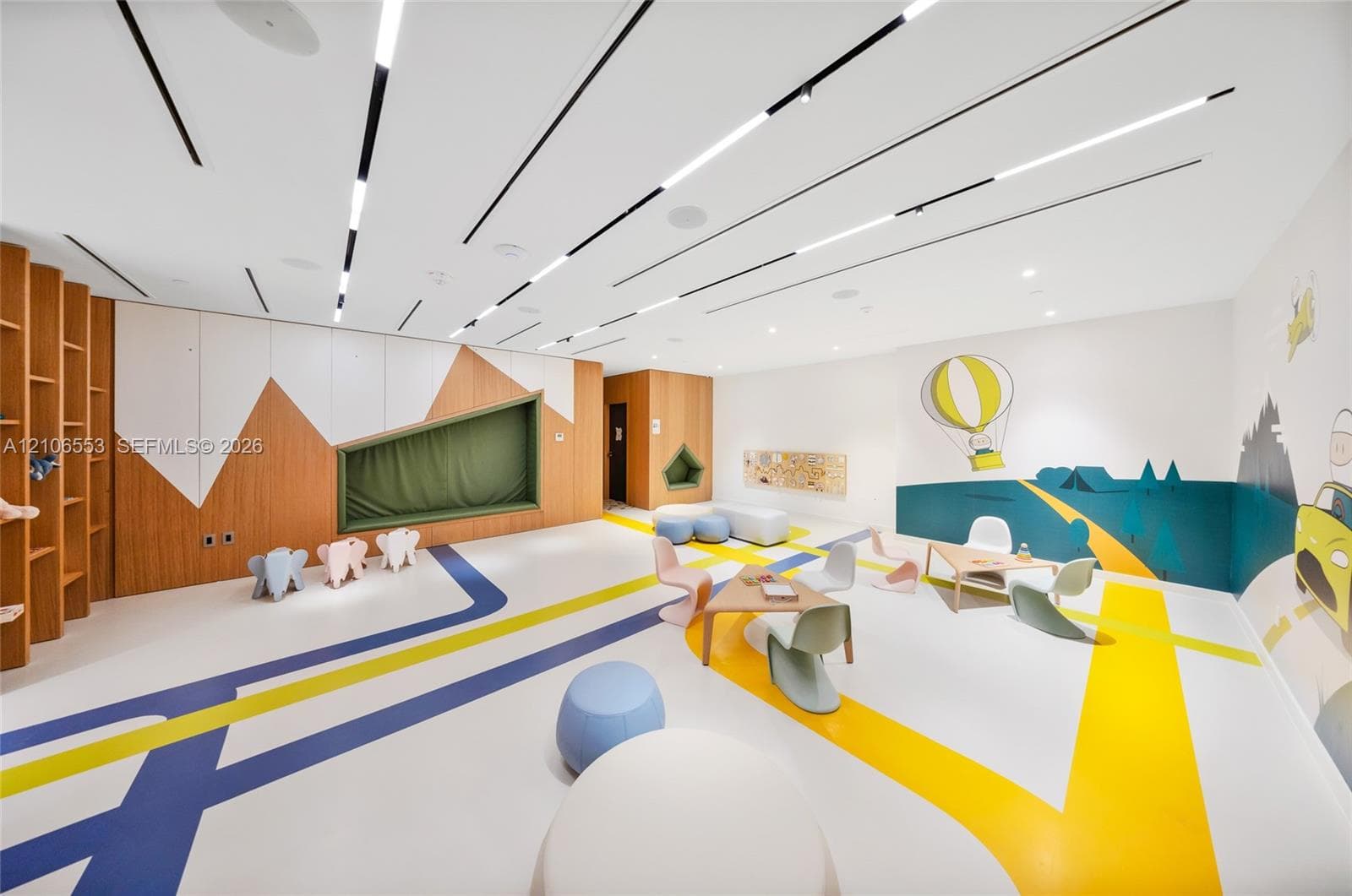 Custom interior featuring recessed linear ceiling lighting, integrated wood-finish wall shelving, a built-in recessed wall nook, and graphic floor detailing