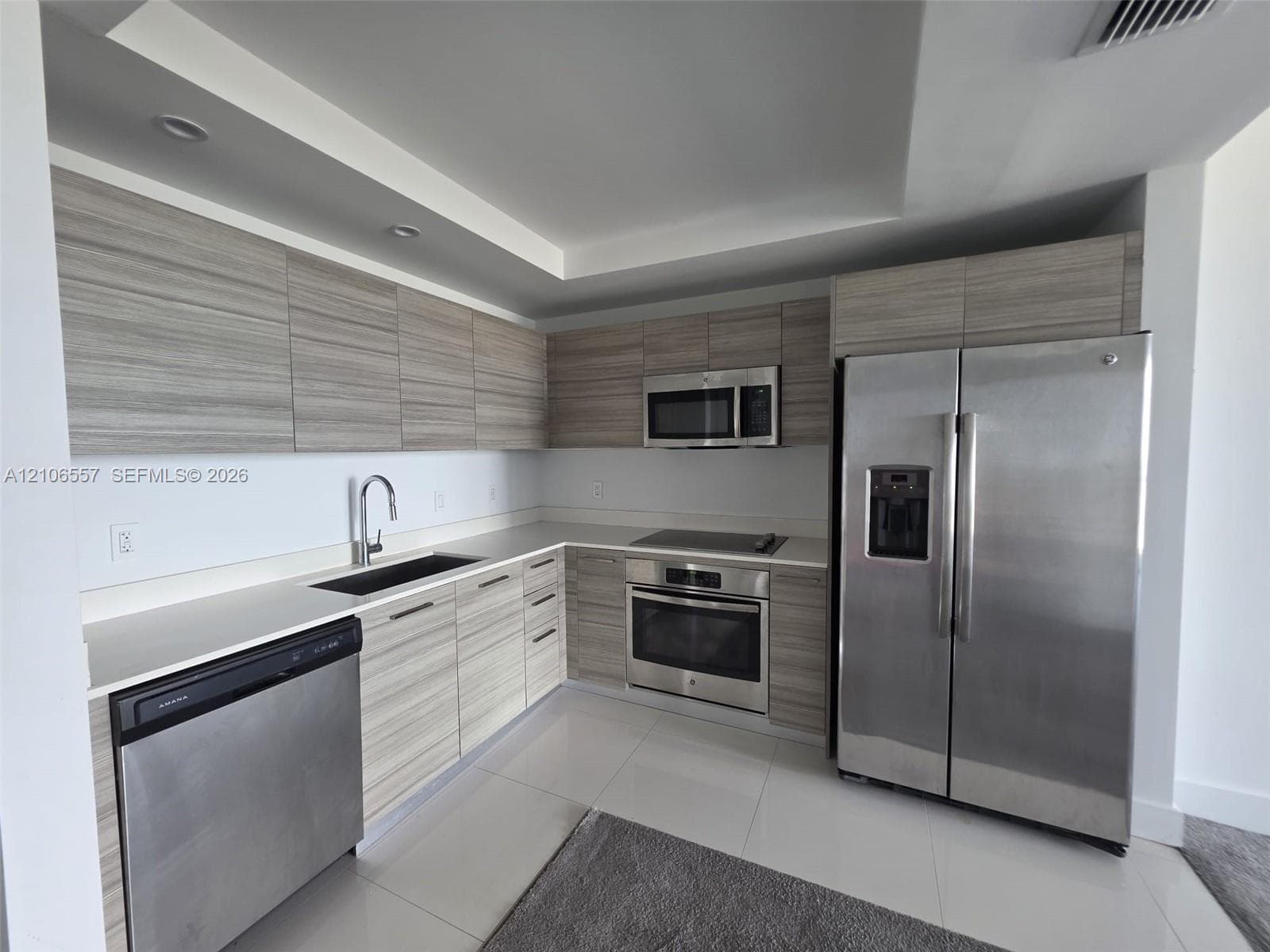 Kitchen featuring horizontal grain wood-finish cabinetry, solid surface countertops, recessed lighting, and stainless steel appliances
