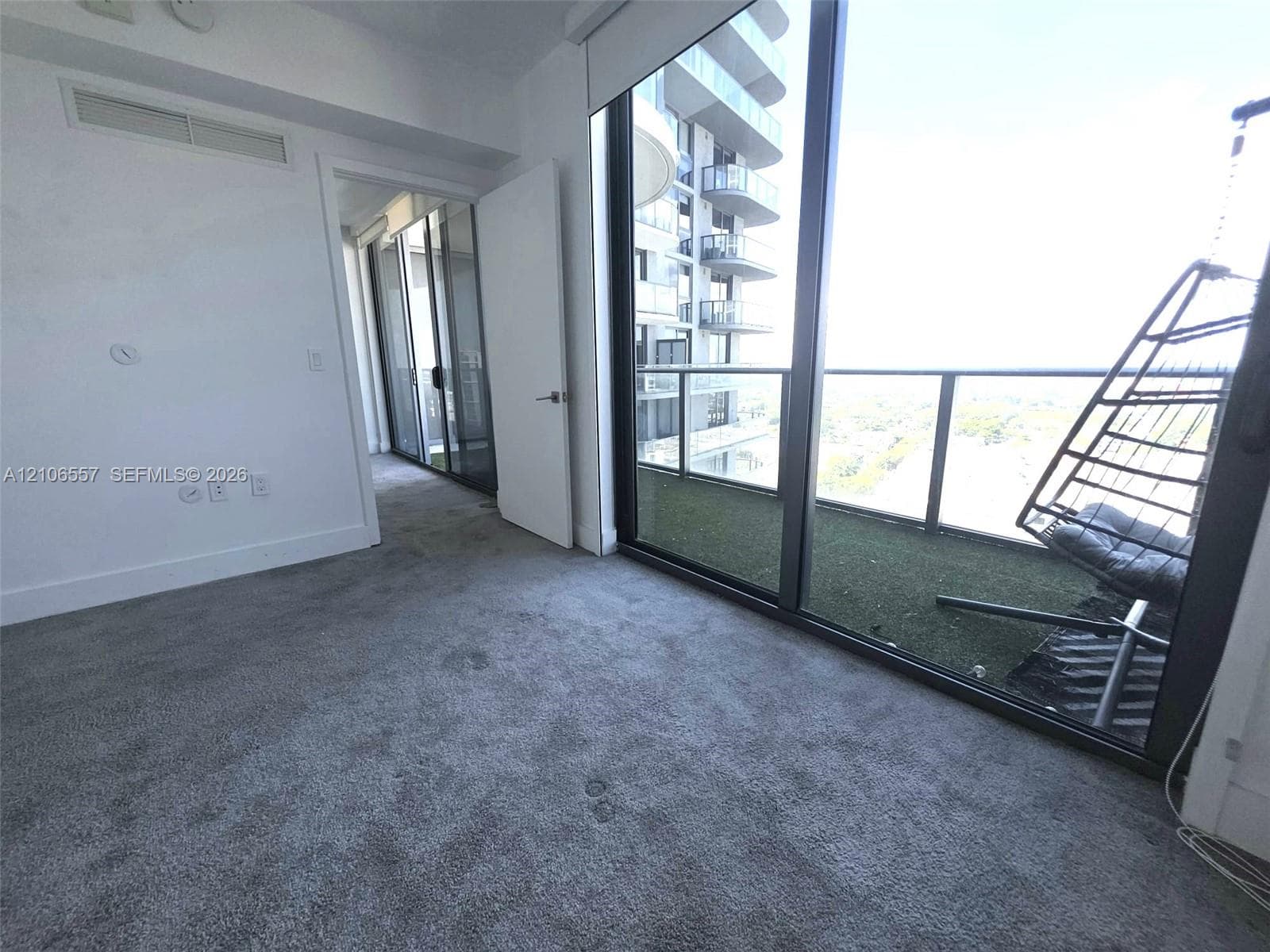Floor-to-ceiling windows, private balcony with integrated turf flooring, and sliding glass door entry