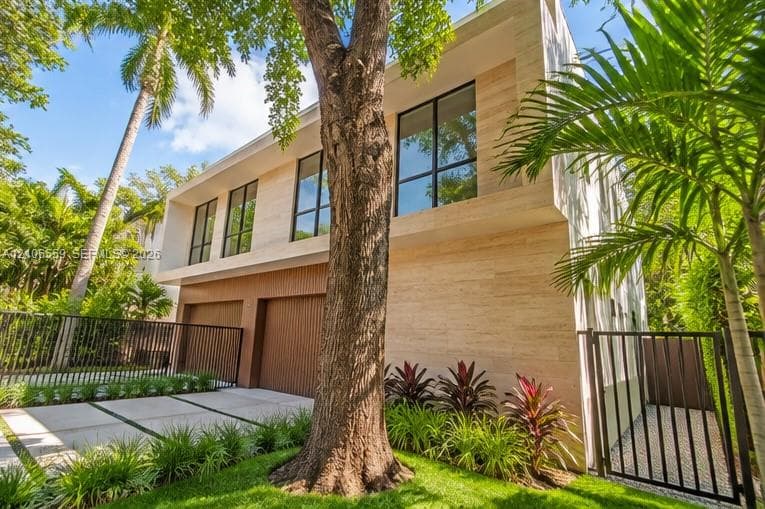Modern two-story exterior featuring linear stone cladding, vertical wood-slat garage doors, and large-format black-frame windows
