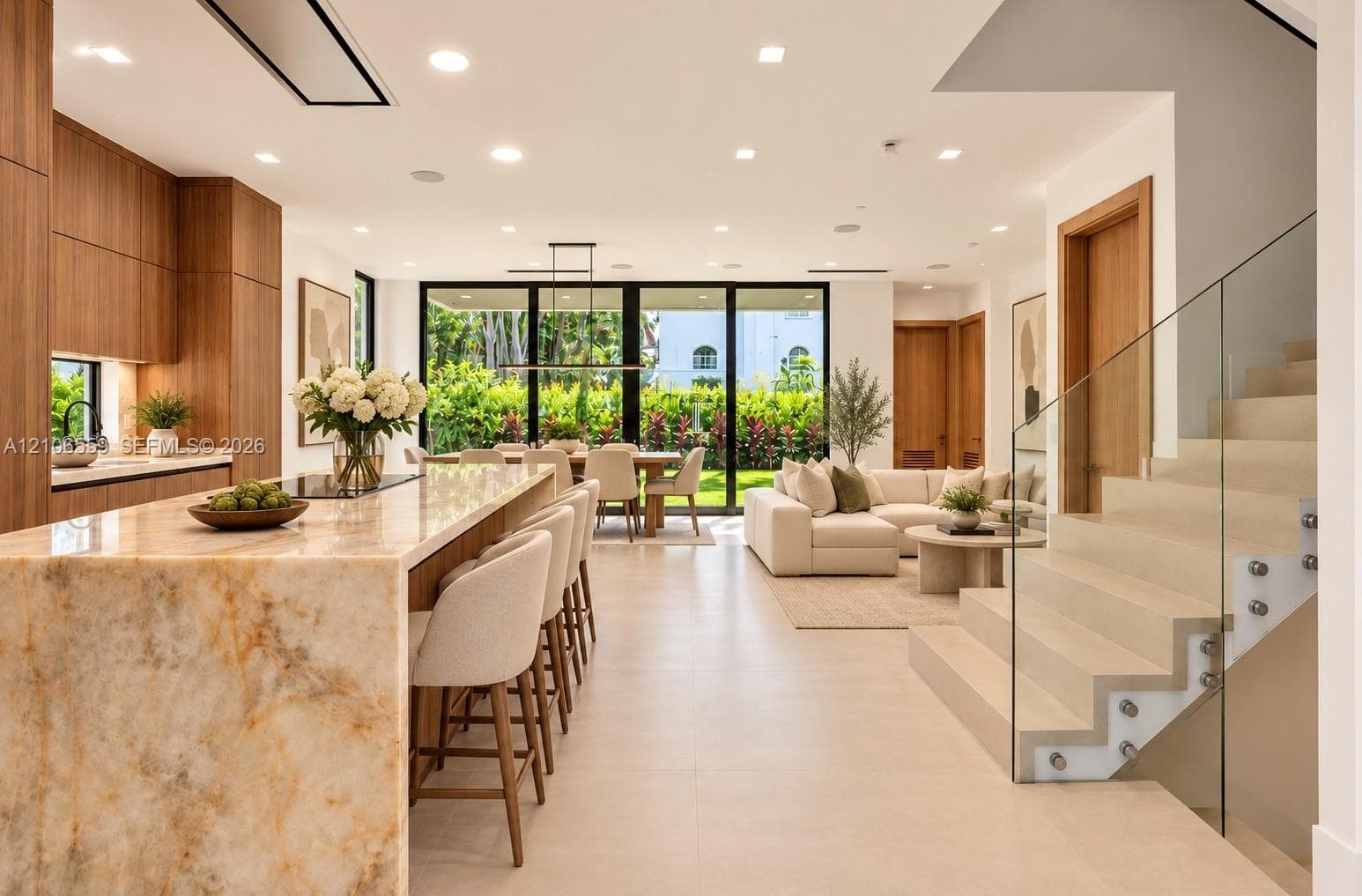 AI staged Kitchen featuring natural stone waterfall island, custom wood-finish cabinetry, porcelain flooring, floor-to-ceiling glass sliding doors, and a glass-paneled staircase